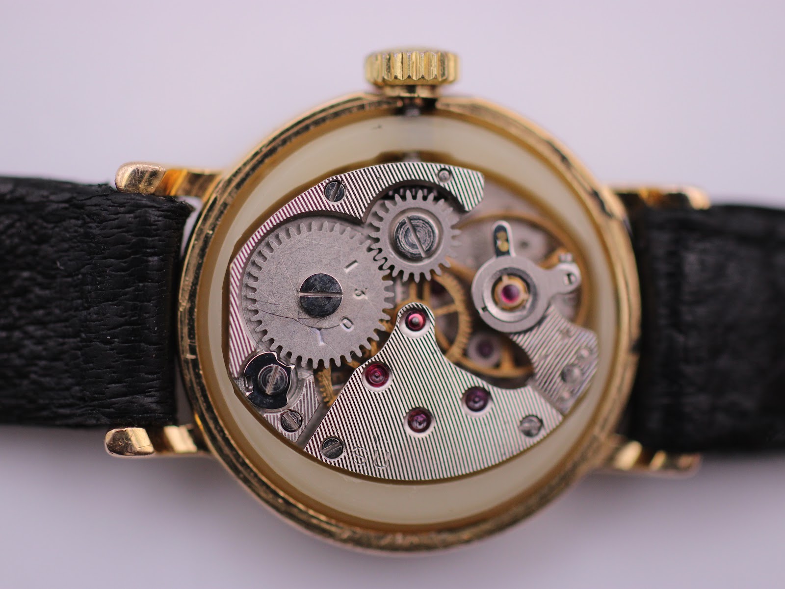 Movement shot of the manual wind mechanism inside the gold tone case.