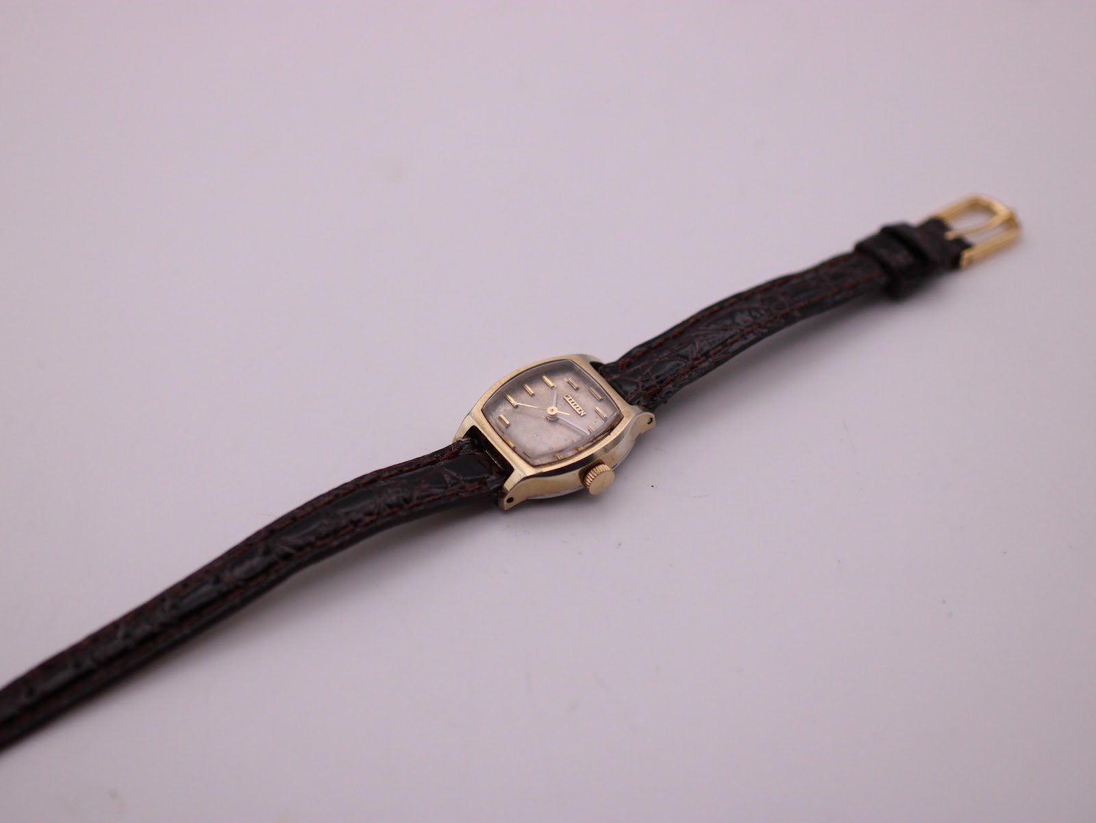 Full top-down view of the Citizen 65-4329 watch on its brown leather strap, displayed on a clear stand.