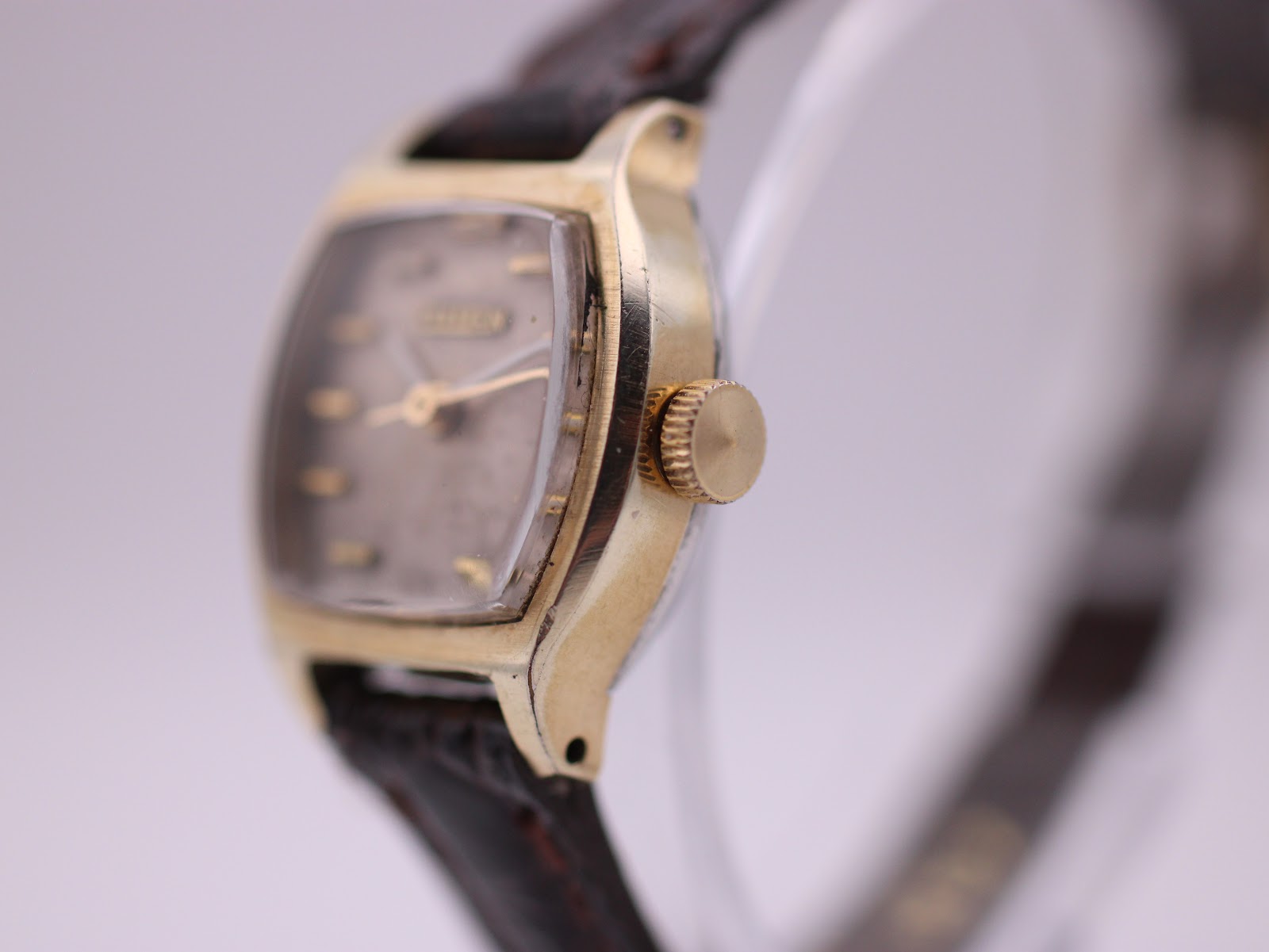 Right side profile of the Citizen watch, highlighting the gold-plated case, crown, and acrylic crystal.