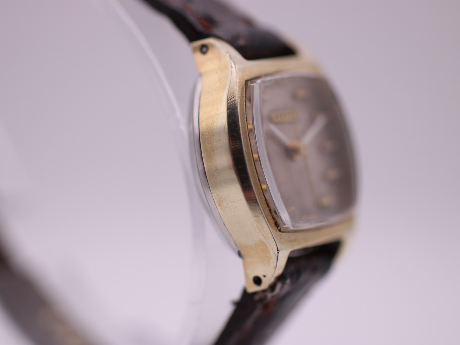 Left side profile of the Citizen watch, showing wear on the gold plating and the curvature of the tonneau case.