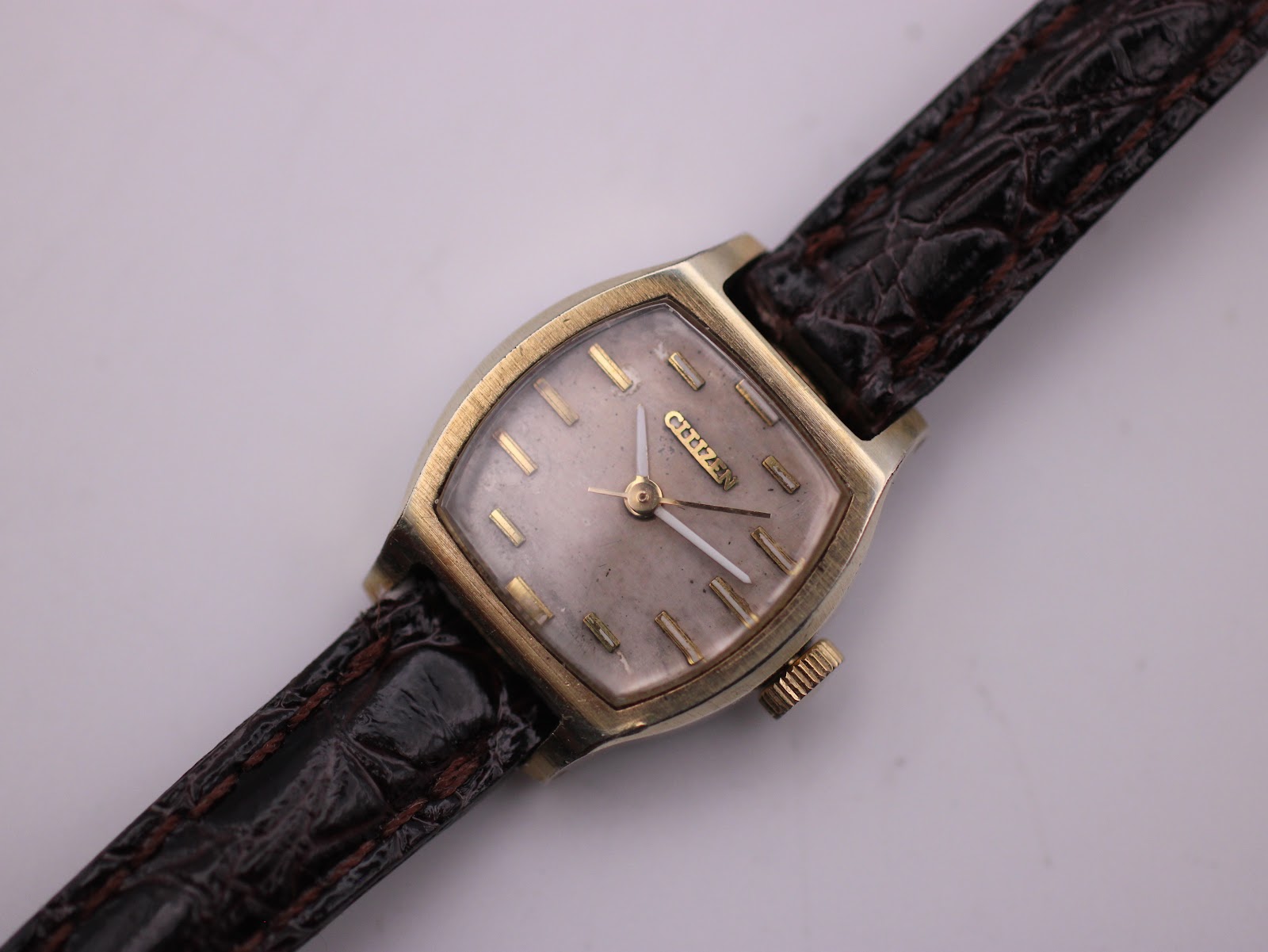 Close-up front view of the Citizen watch dial, showing the champagne texture, applied gold baton indices, and hands.