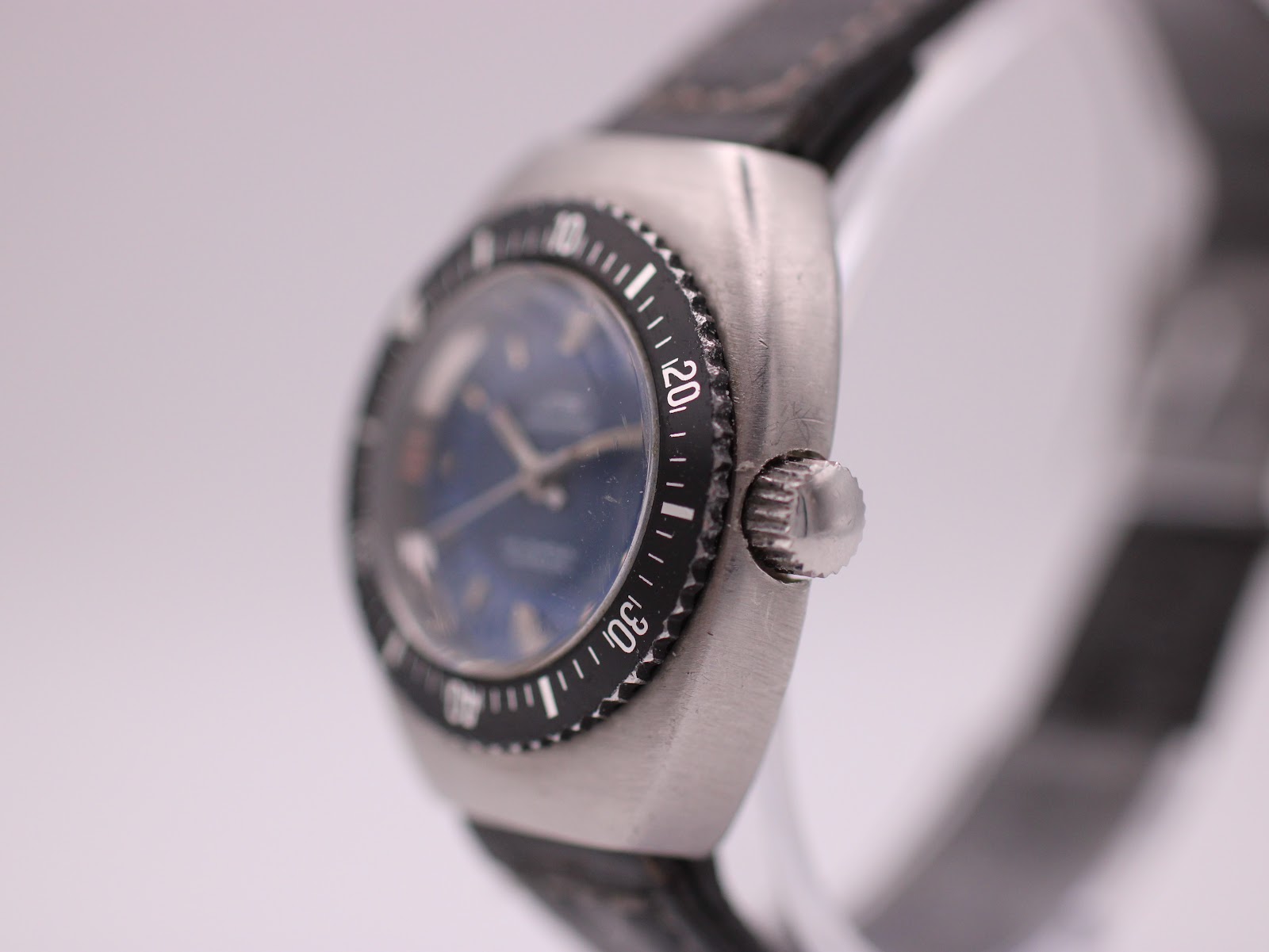Side view of the UNTO watch, showing the brushed stainless steel tonneau case and serrated bezel edge.
