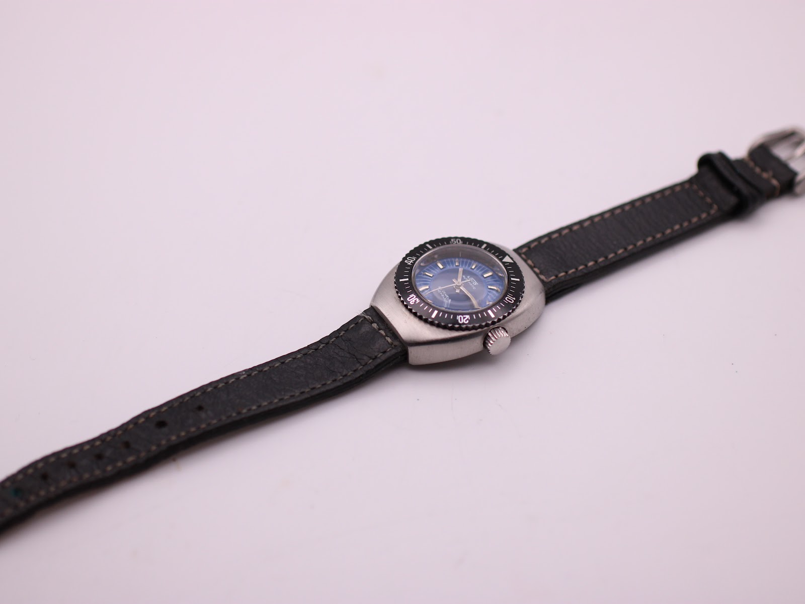 Full length view of the UNTO automatic watch on its black leather strap, on a white background.