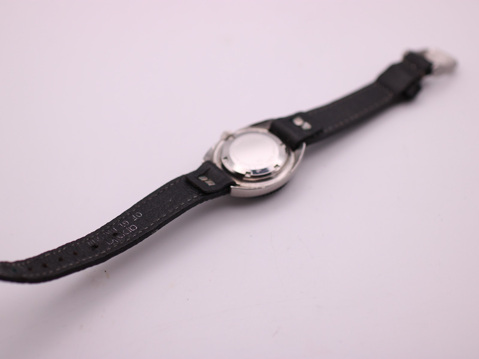 Rear view of the UNTO watch and strap, showing the strap's underside with 'GENUINE LEATHER' text.