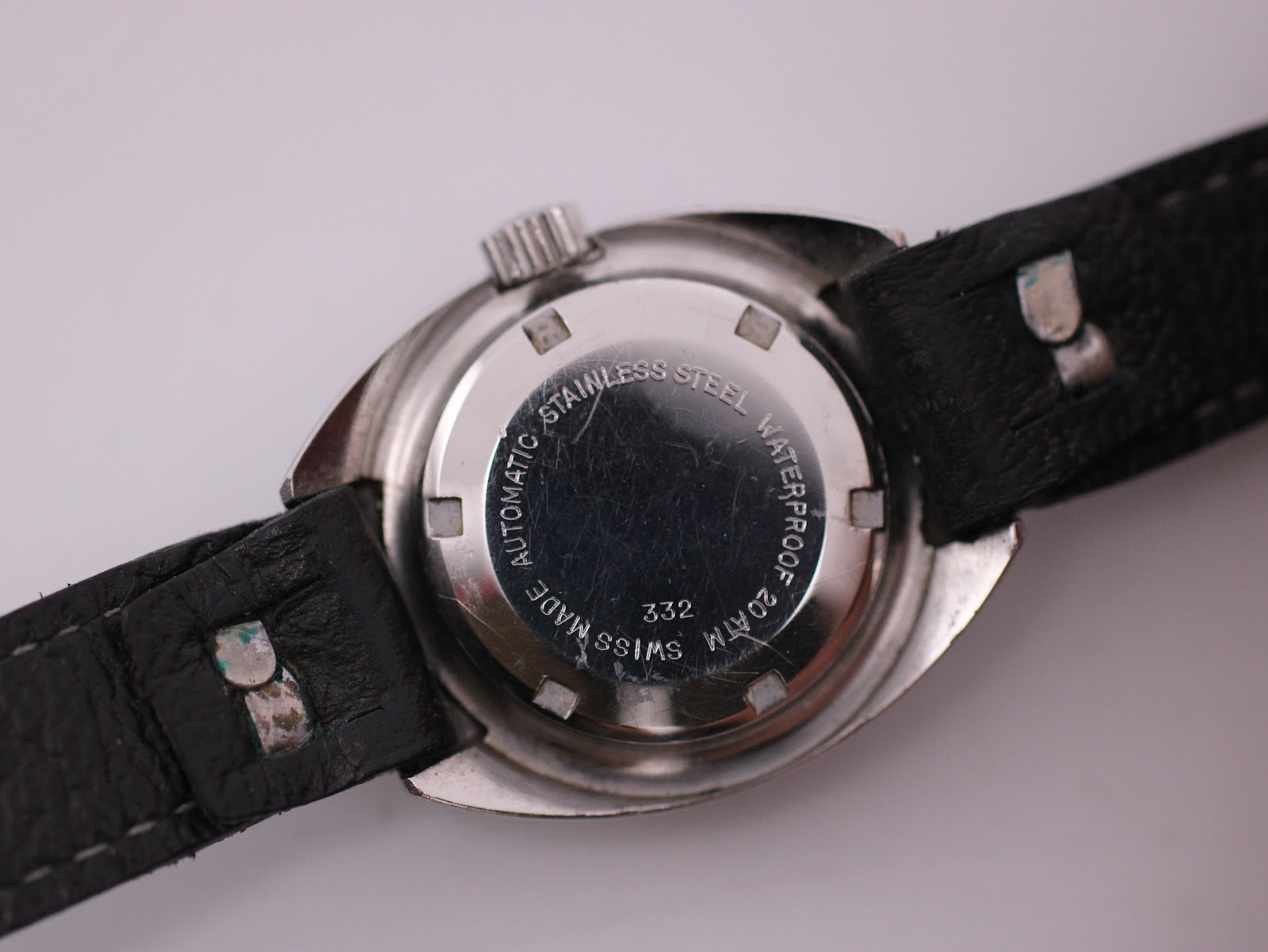 Close-up of the stainless steel case back, showing 'AUTOMATIC STAINLESS STEEL WATERPROOF 20 ATM SWISS MADE 332' engravings.