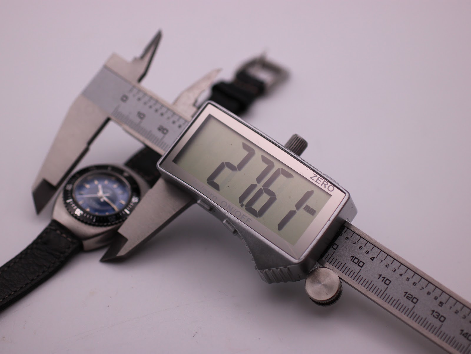 Digital caliper measuring the watch case diameter at 27.61mm.