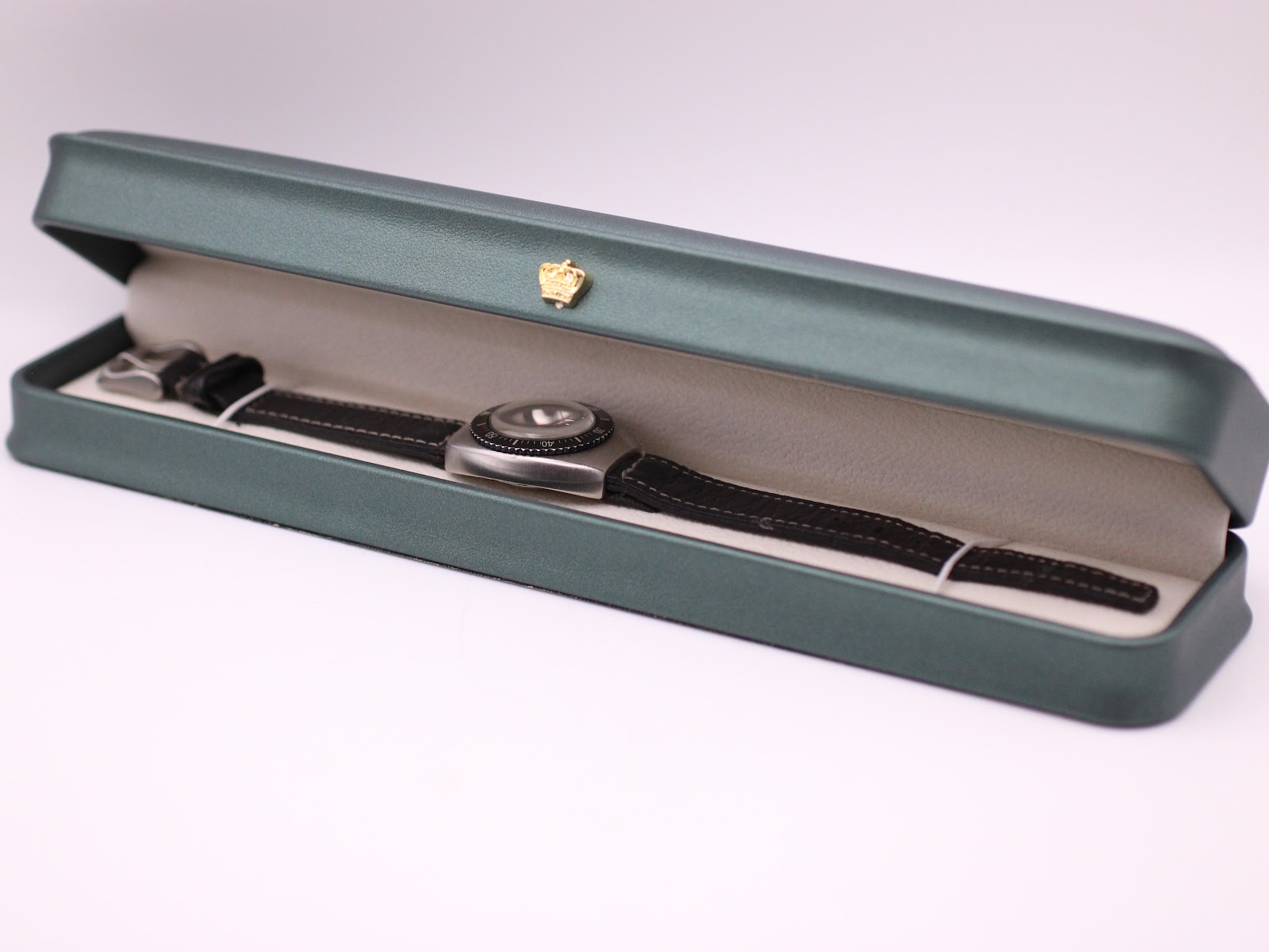 The UNTO watch displayed inside a green presentation box with a gold crown emblem.