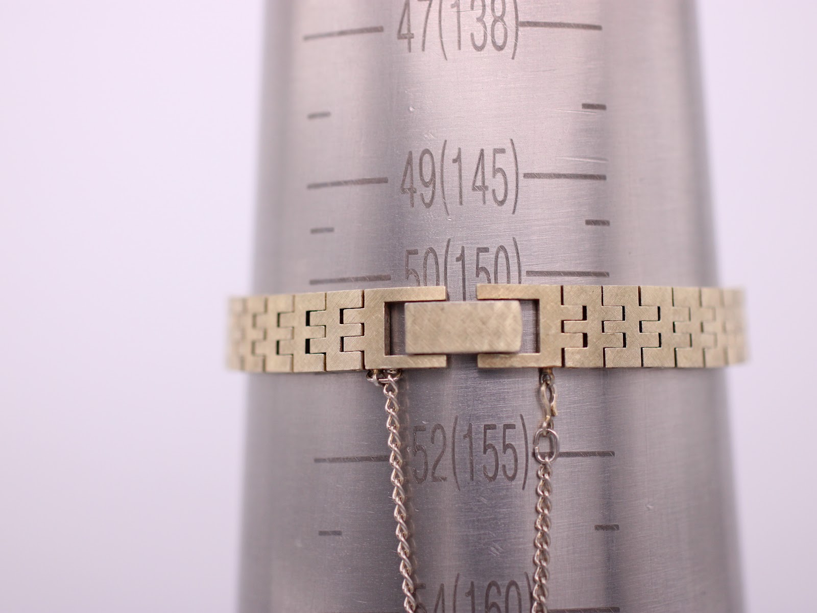 The gold-tone integrated bracelet of the Seiko watch on a wrist sizing gauge, showing a circumference measurement of 15.5cm.
