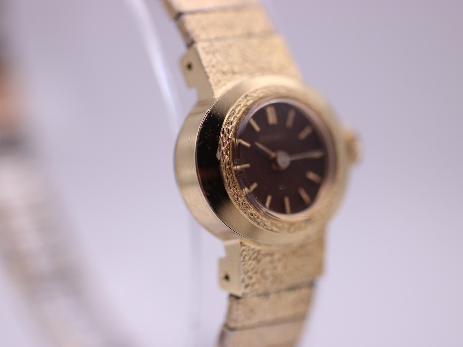 Left-side profile of the gold-plated Seiko watch case, highlighting the textured bezel and the gold-tone expanding bracelet.