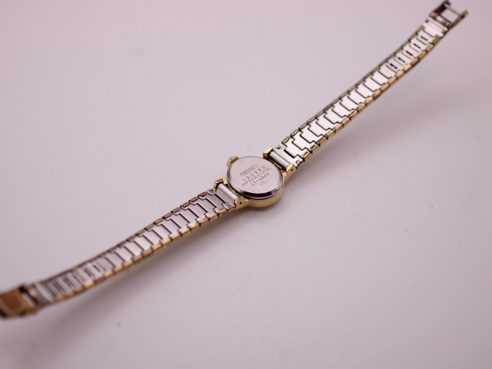 Rear view of the Seiko watch, showing the stainless steel case back engraving and the two-tone construction of the bracelet.