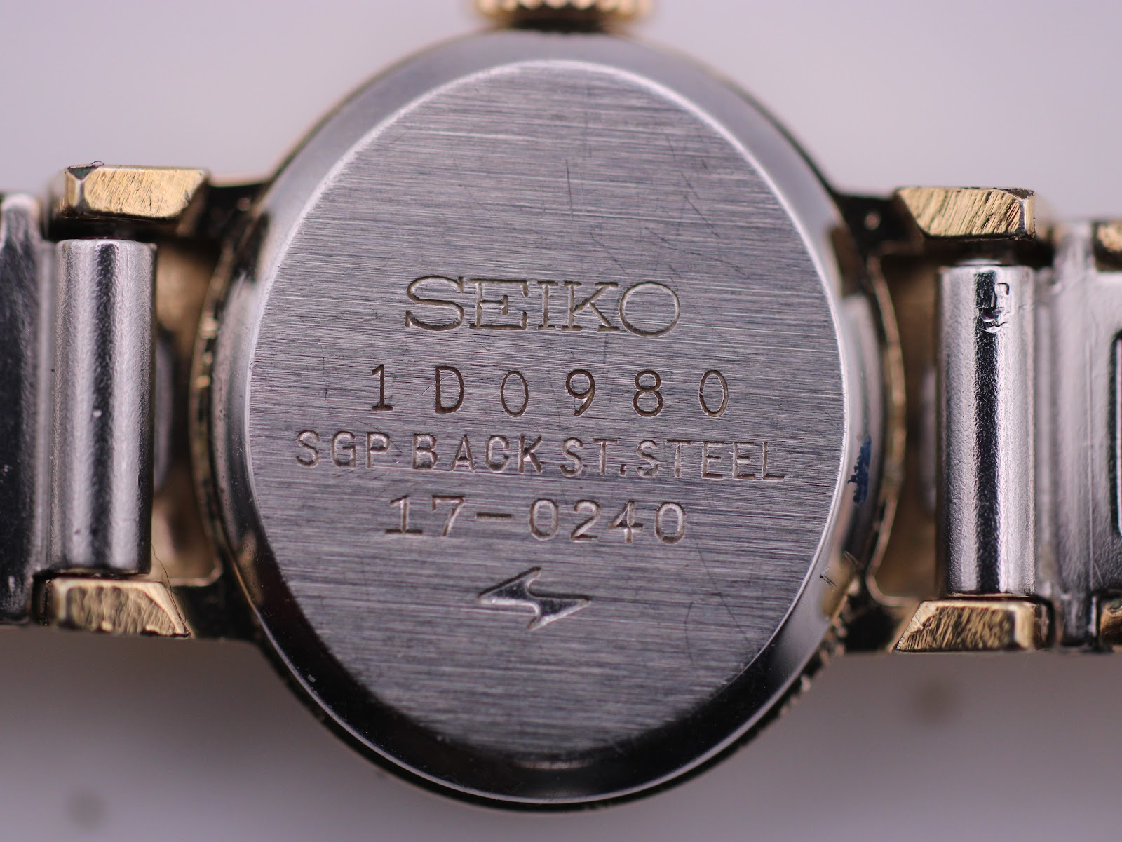 Detailed close-up of the Seiko watch's stainless steel case back, showing the serial number (1D0980) and model number (17-0240) engravings.