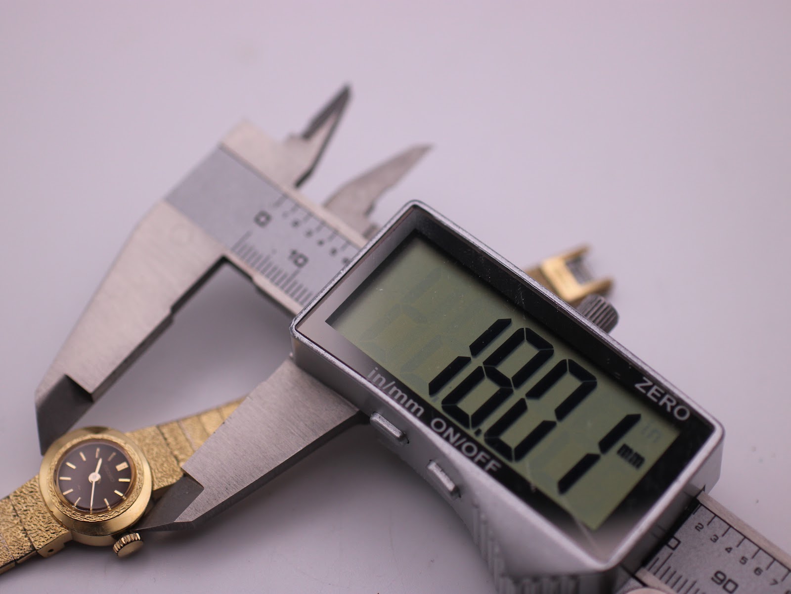 Digital caliper measuring the Seiko watch case diameter, displaying 18.1mm.