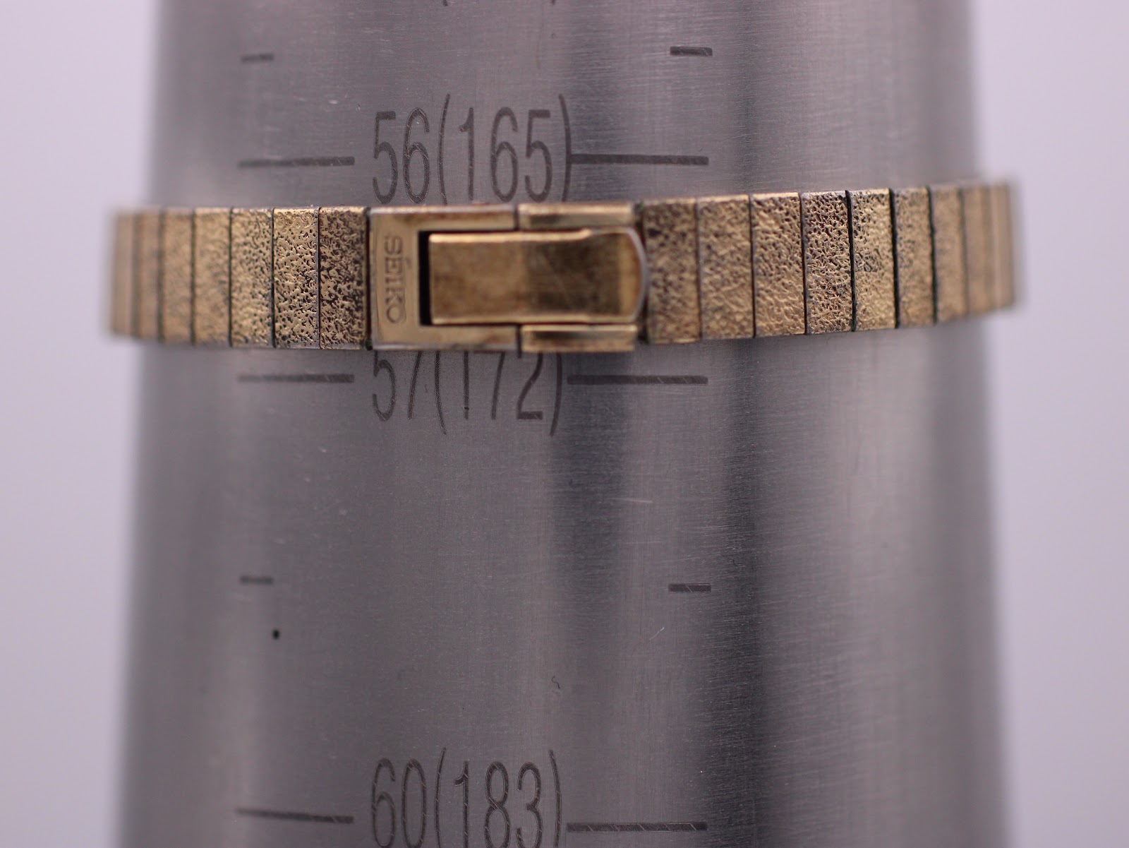 Close-up of the vintage Seiko's gold-tone expanding bracelet clasp, signed 'SEIKO', on a wrist sizing gauge indicating 165mm (16.5cm).