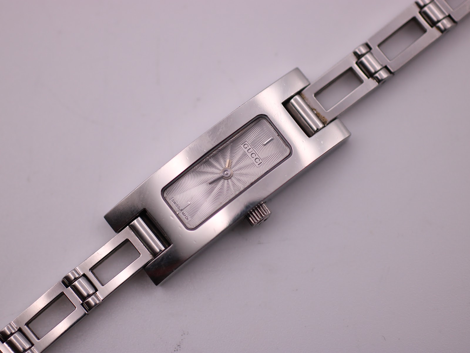 Close-up of the Gucci 3900L watch dial, crown, and first links of the integrated bracelet.