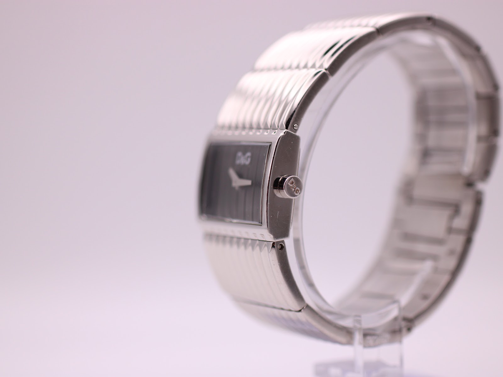 Side view of the D&G watch on a stand, showing the signed crown and bracelet texture.