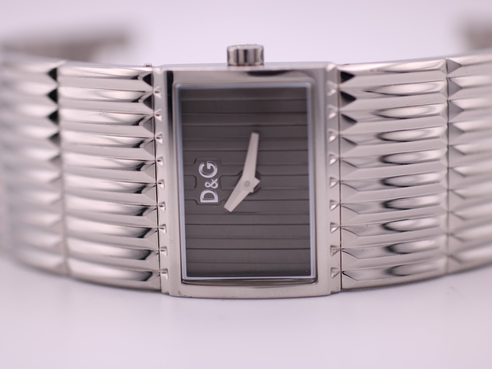 Close-up front view of the D&G watch dial, showing the grey vertical stripe texture and D&G logo.