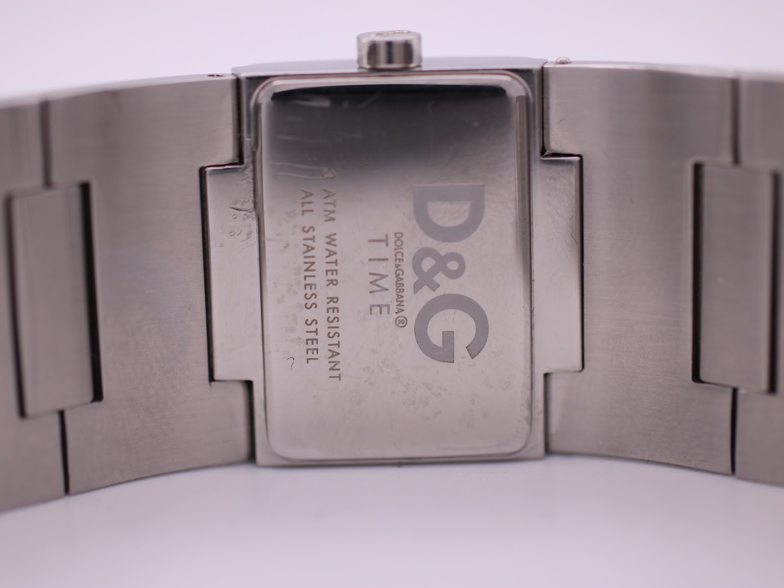 Close-up of the watch case back, showing 'D&G Time', '3 ATM Water Resistant', and 'All Stainless Steel' engravings.