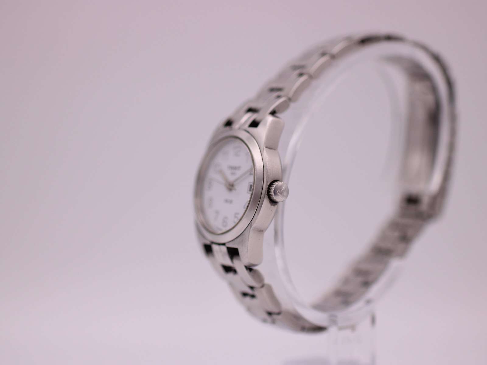 Side view of the Tissot PR 50 watch, showing the crown with the Tissot logo and the curve of the steel bracelet.