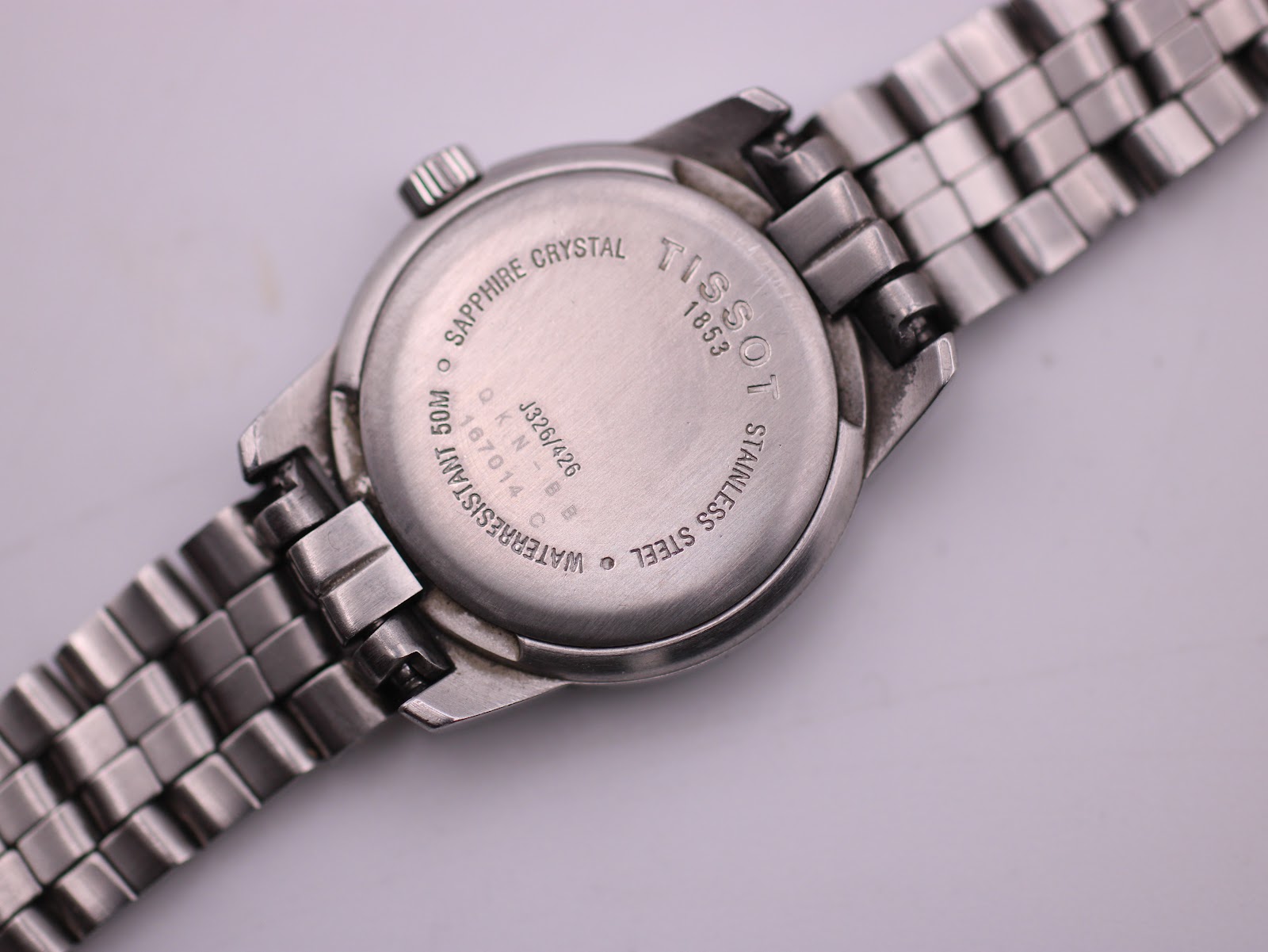 Close-up of the Tissot PR 50 stainless steel case back, engraved with 'Sapphire Crystal', 'Waterresistant 50M', and model/serial details.