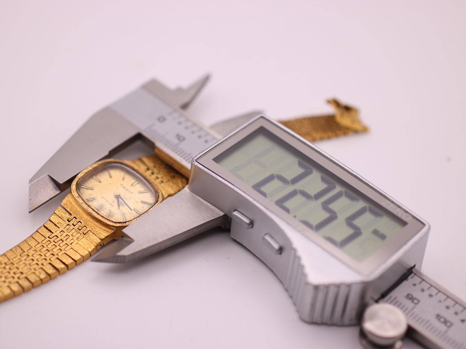 The Tissot Stylist watch being measured by a digital caliper, displaying a case size of 22.55mm.