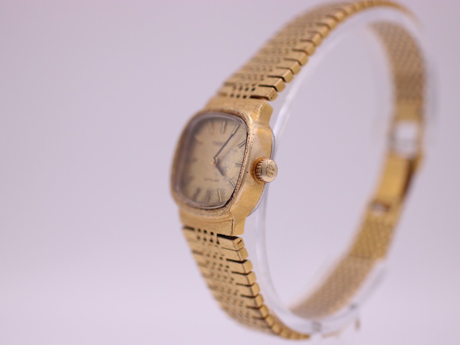 Angled side view of the Tissot Stylist, highlighting the textured gold cushion case and original crown.