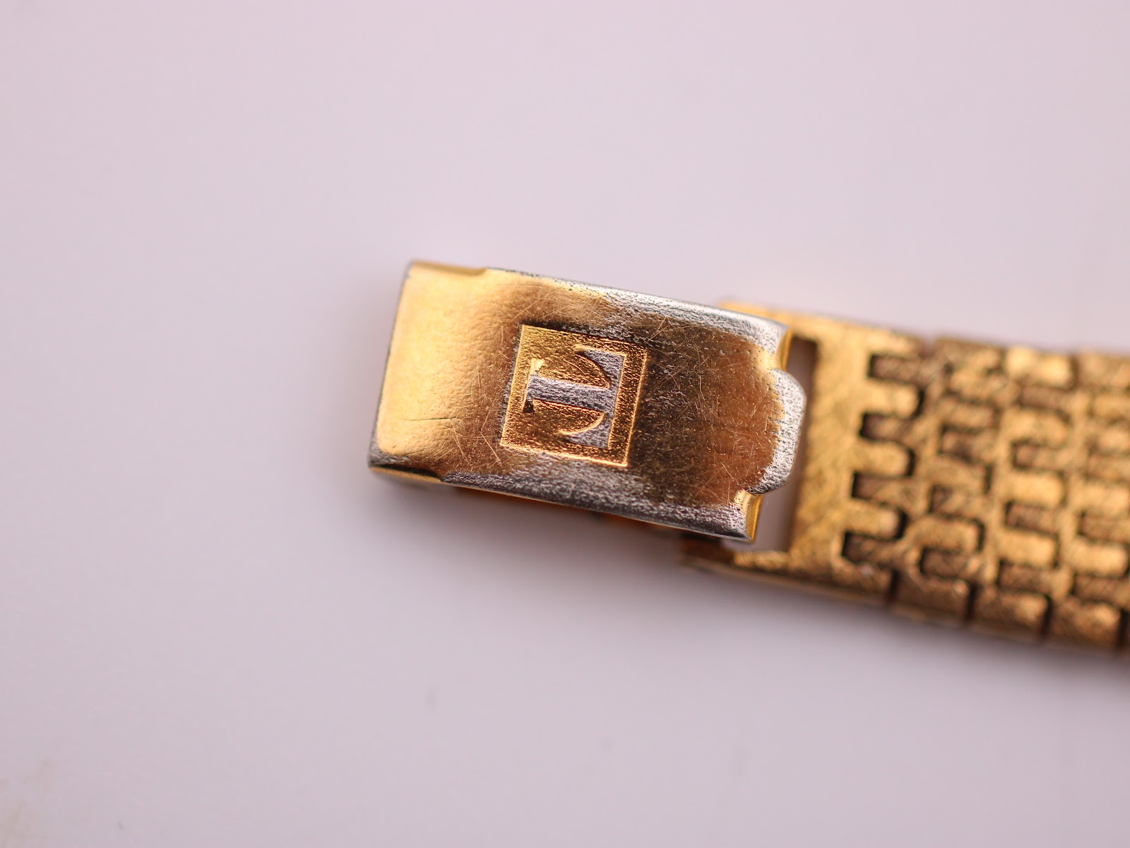 Close-up of the folding clasp on the Tissot Stylist bracelet, displaying the embossed 'T' logo.