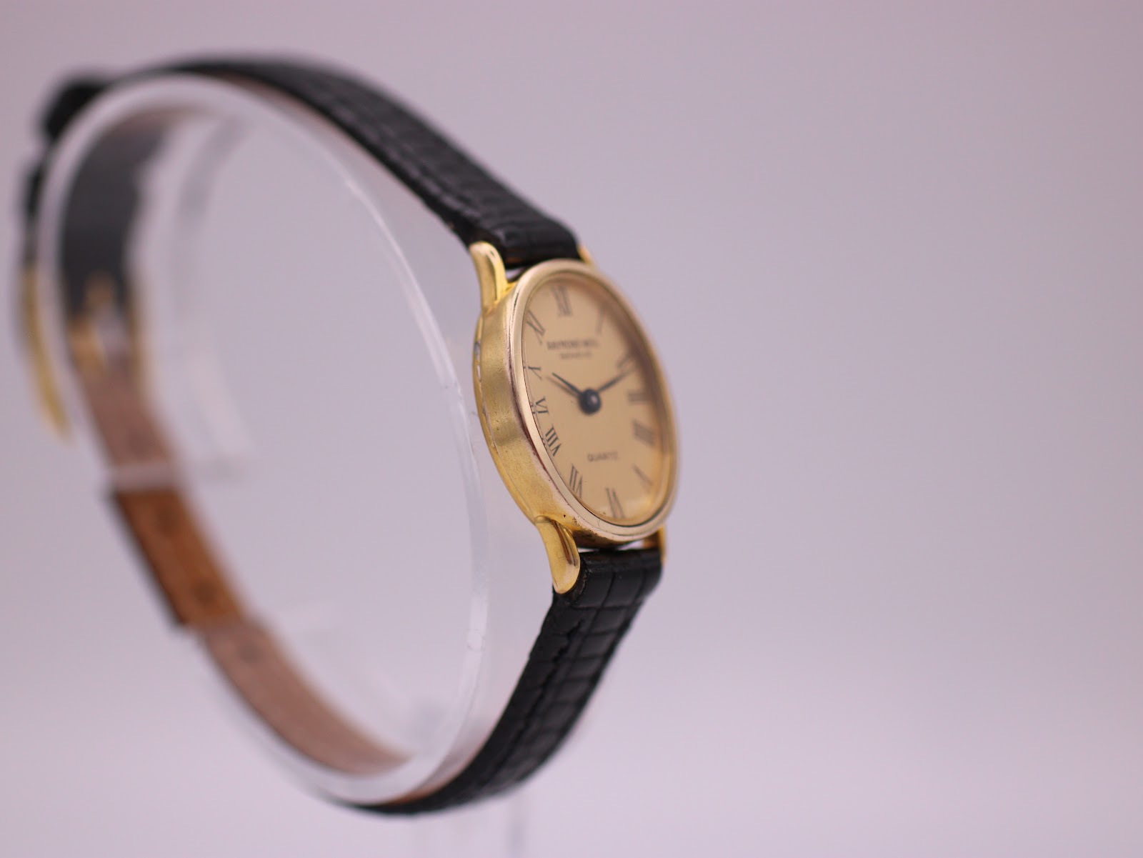 Another angled side view of the Raymond Weil watch, highlighting the slender gold case and classic profile.