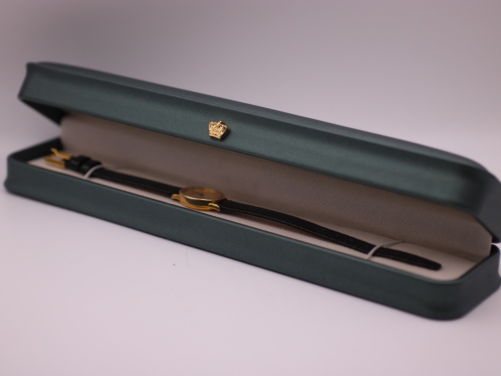 The Raymond Weil watch resting inside a generic green leatherette presentation box, a common studio prop.