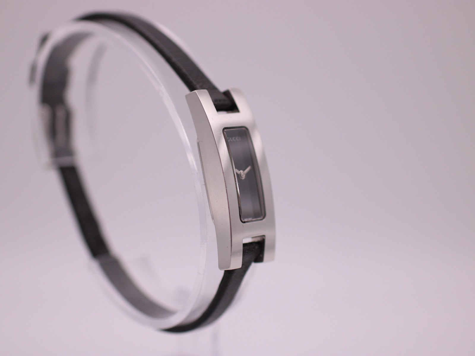Angled side view of the Gucci 3900L watch on a clear stand.