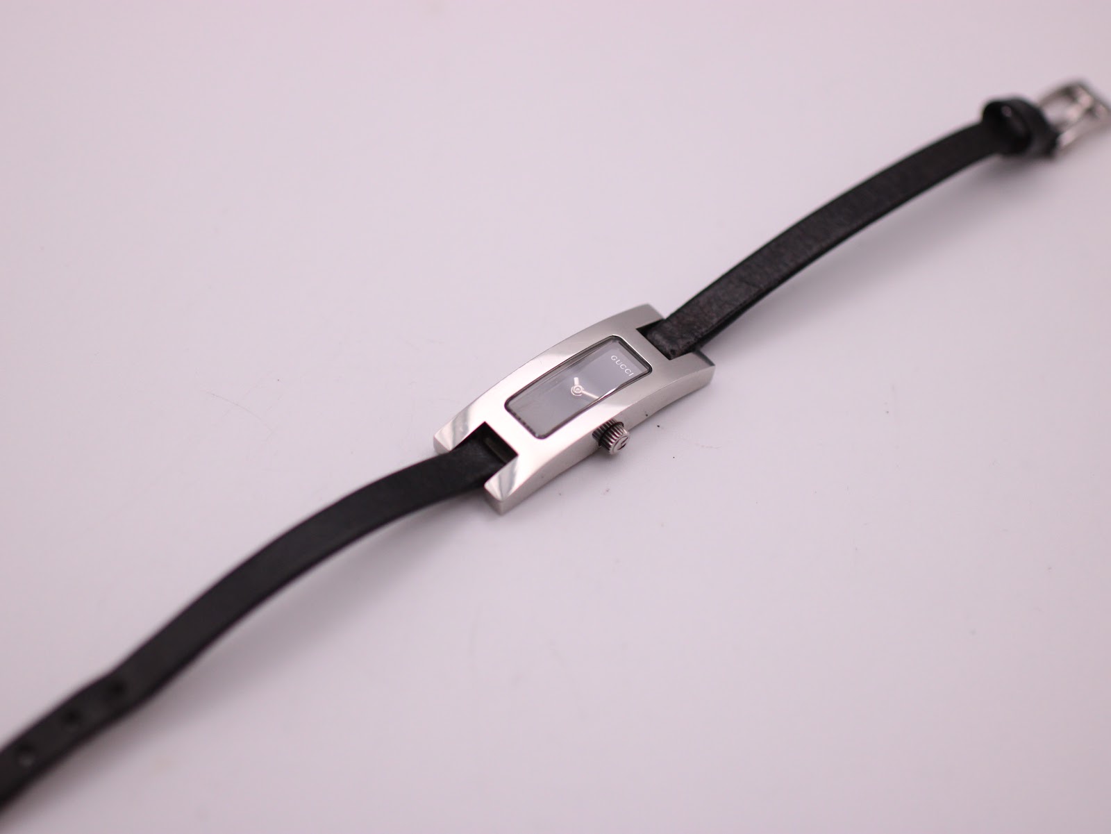 Overhead view of the Gucci 3900L watch laid flat, showing the full black leather strap and buckle.
