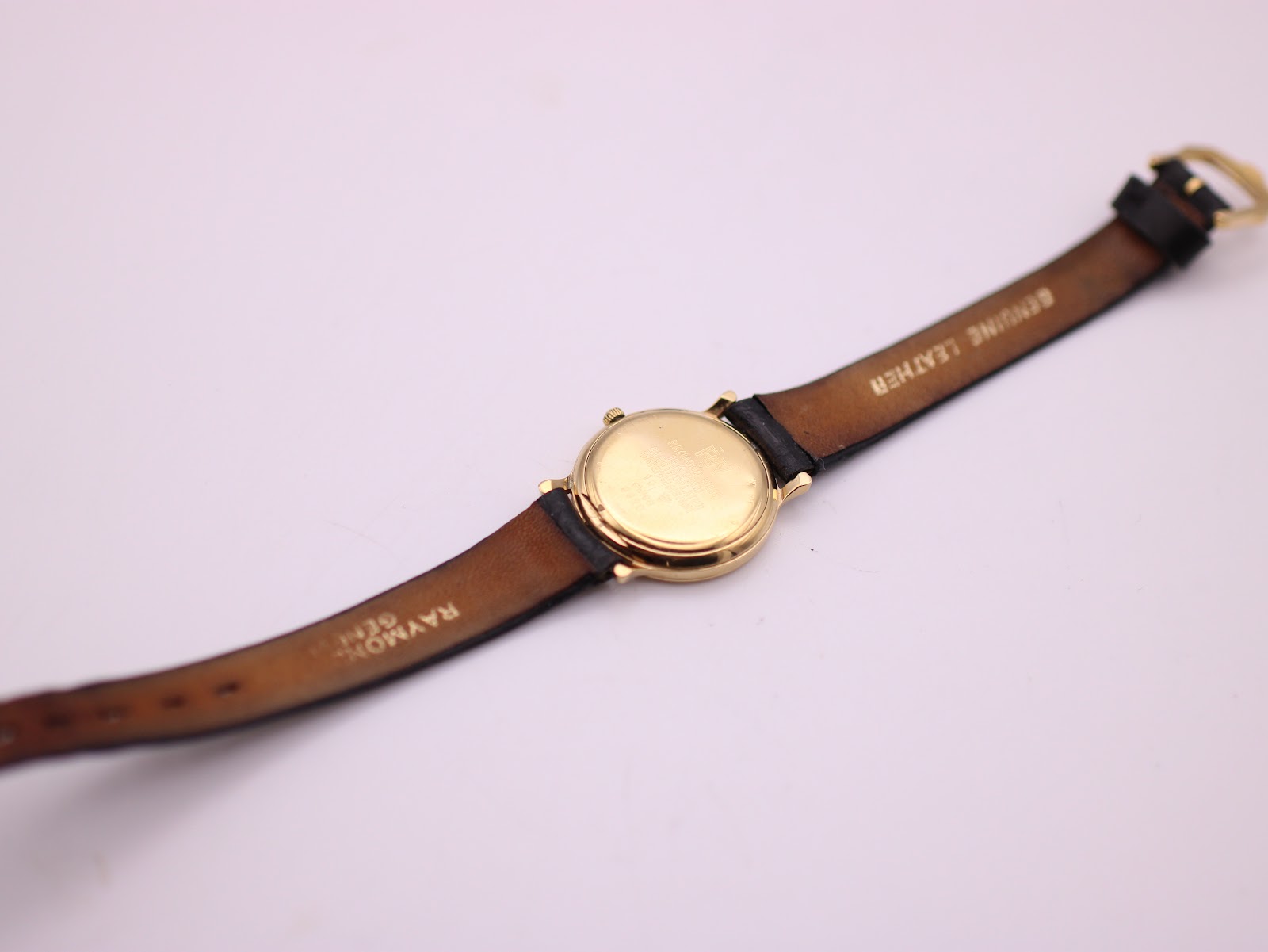 Back view of the Raymond Weil watch and strap, showing 'GENUINE LEATHER' and 'RAYMOND WEIL GENEVE' markings on the strap interior.