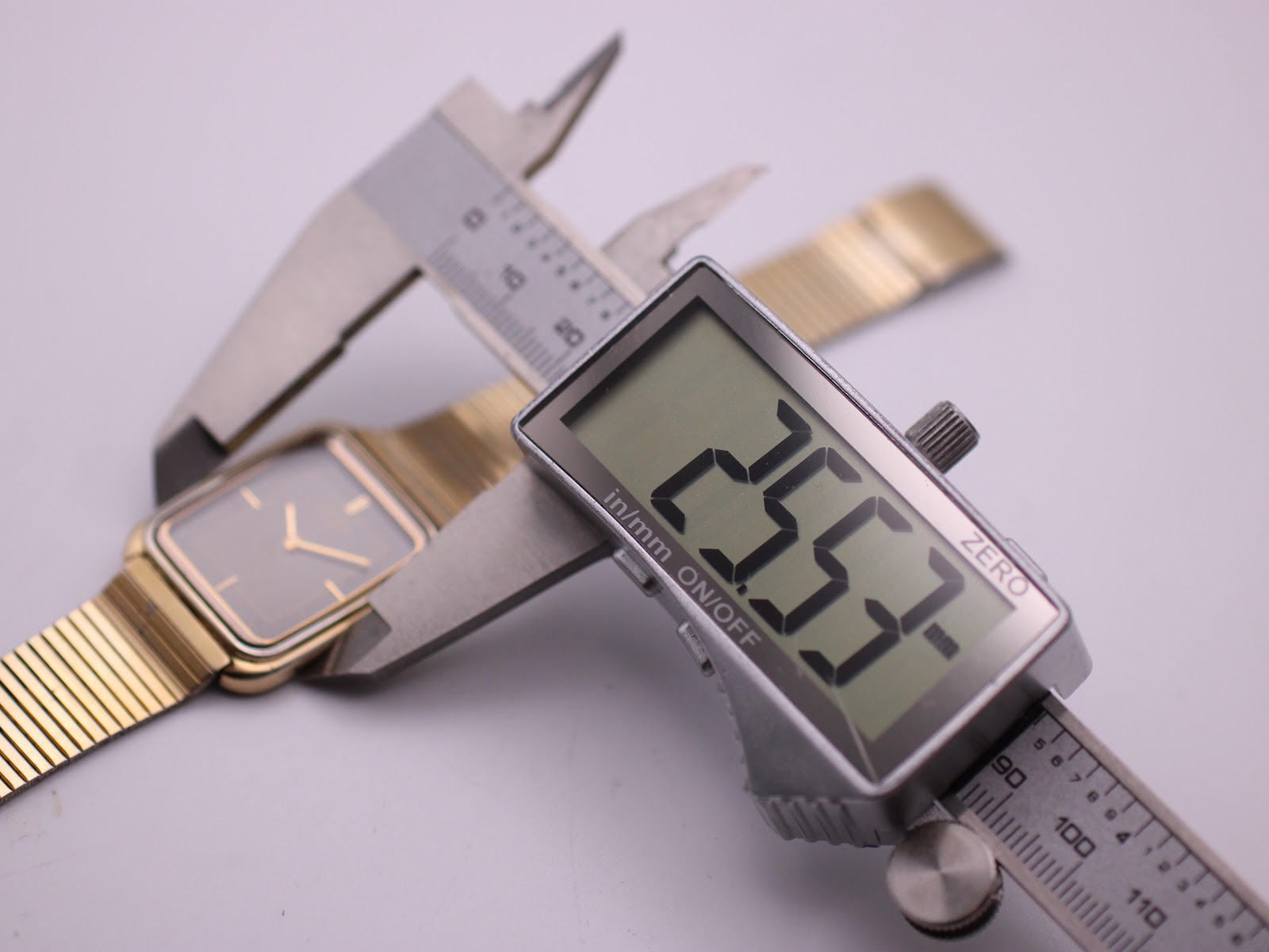 Digital caliper measuring the case width of the Seiko watch, displaying a reading of 25.57mm.