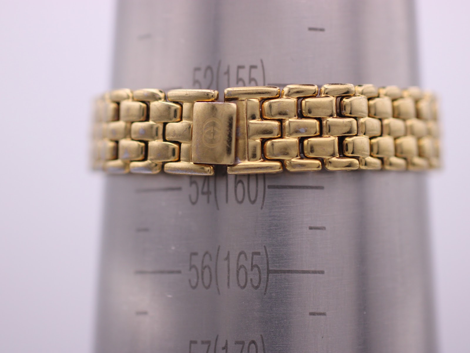 Close-up of the watch bracelet clasp on a wrist sizing gauge, indicating a wrist circumference of 155mm / 15.5cm, with the signed Gucci logo.