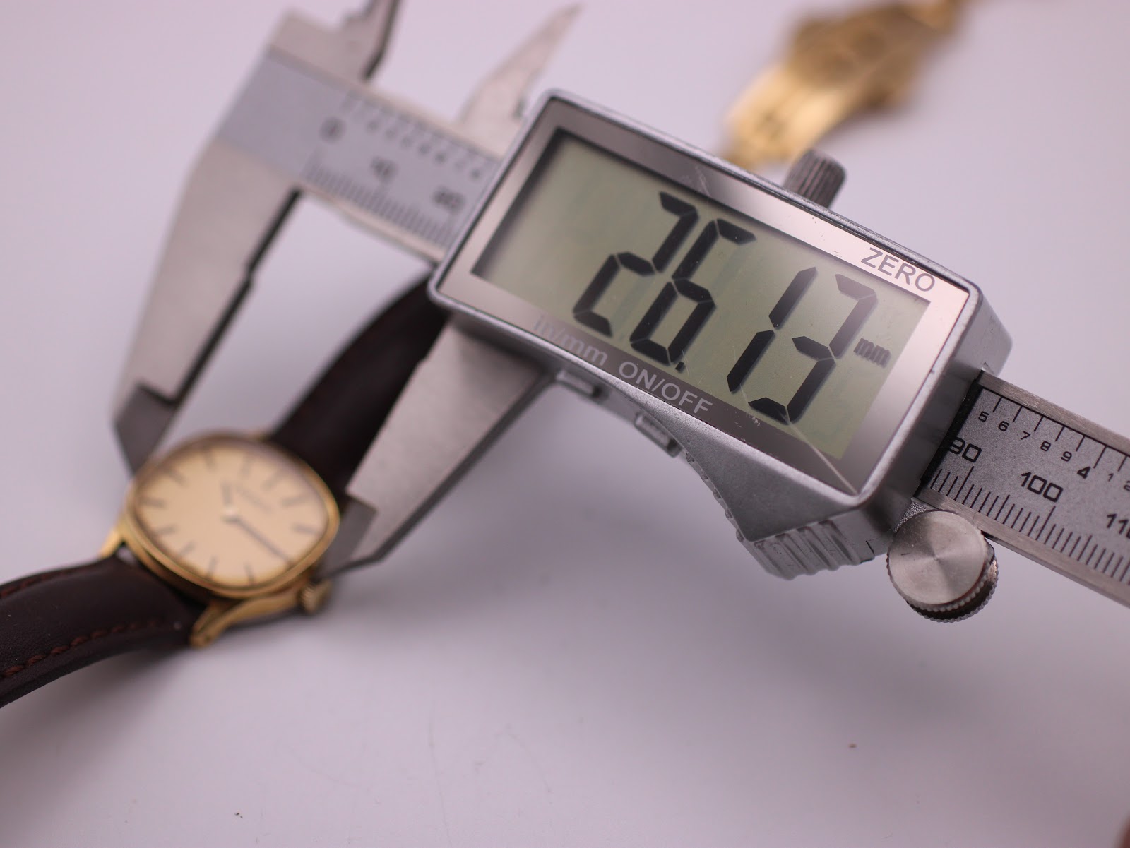 Digital caliper measuring the watch case diameter at 26.13mm.