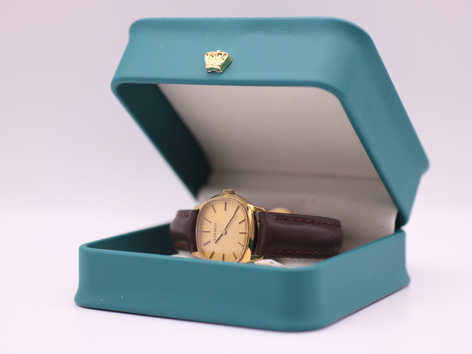 The Tissot watch displayed in a generic green leatherette presentation box.