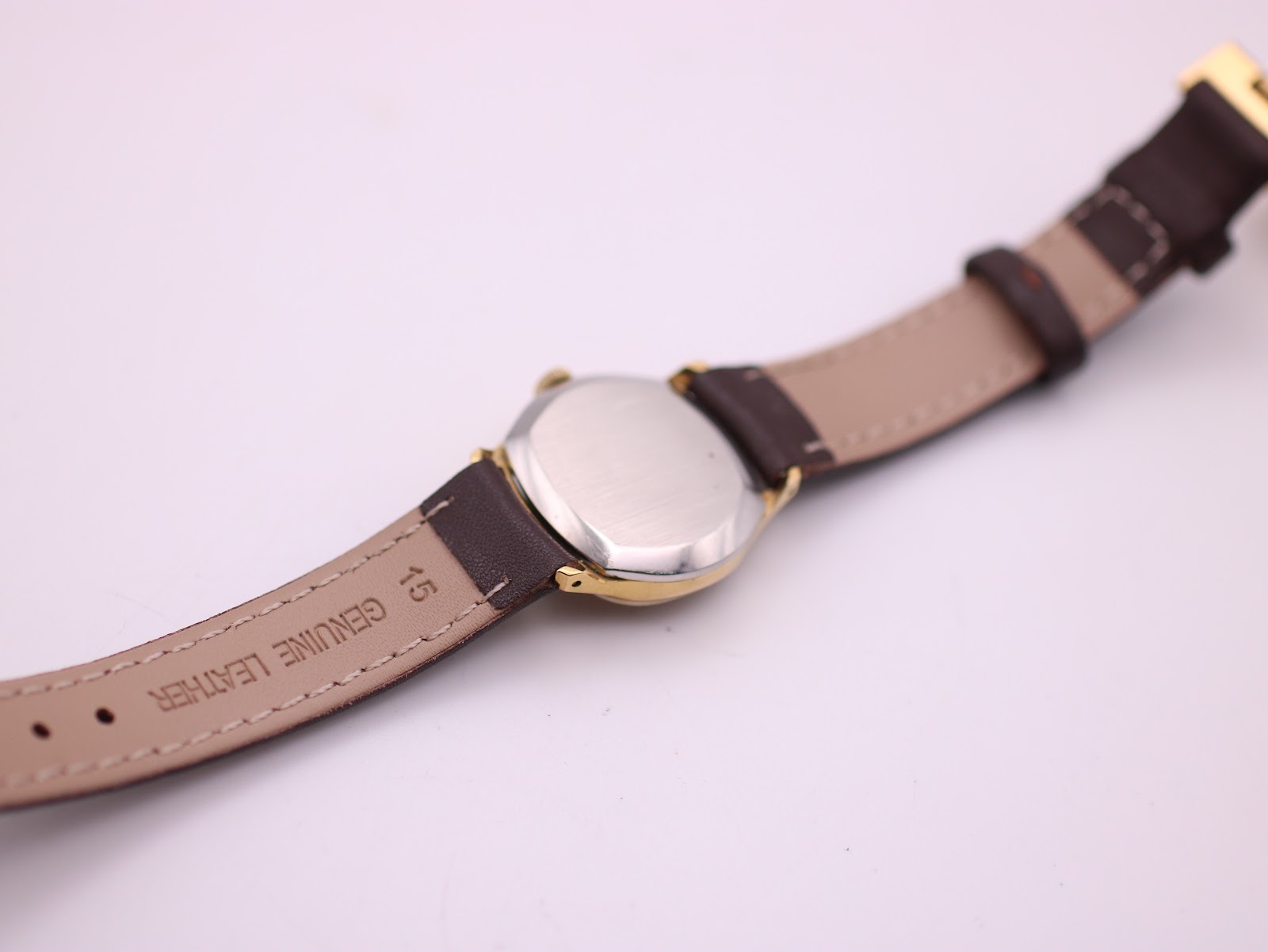 Rear view of the watch showing the stainless steel case back and "Genuine Leather" marking on the brown strap, lug width 15mm visible.