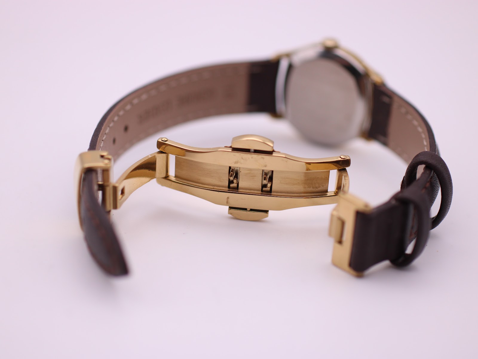 Close-up of the gold-tone deployant clasp on the brown leather strap.