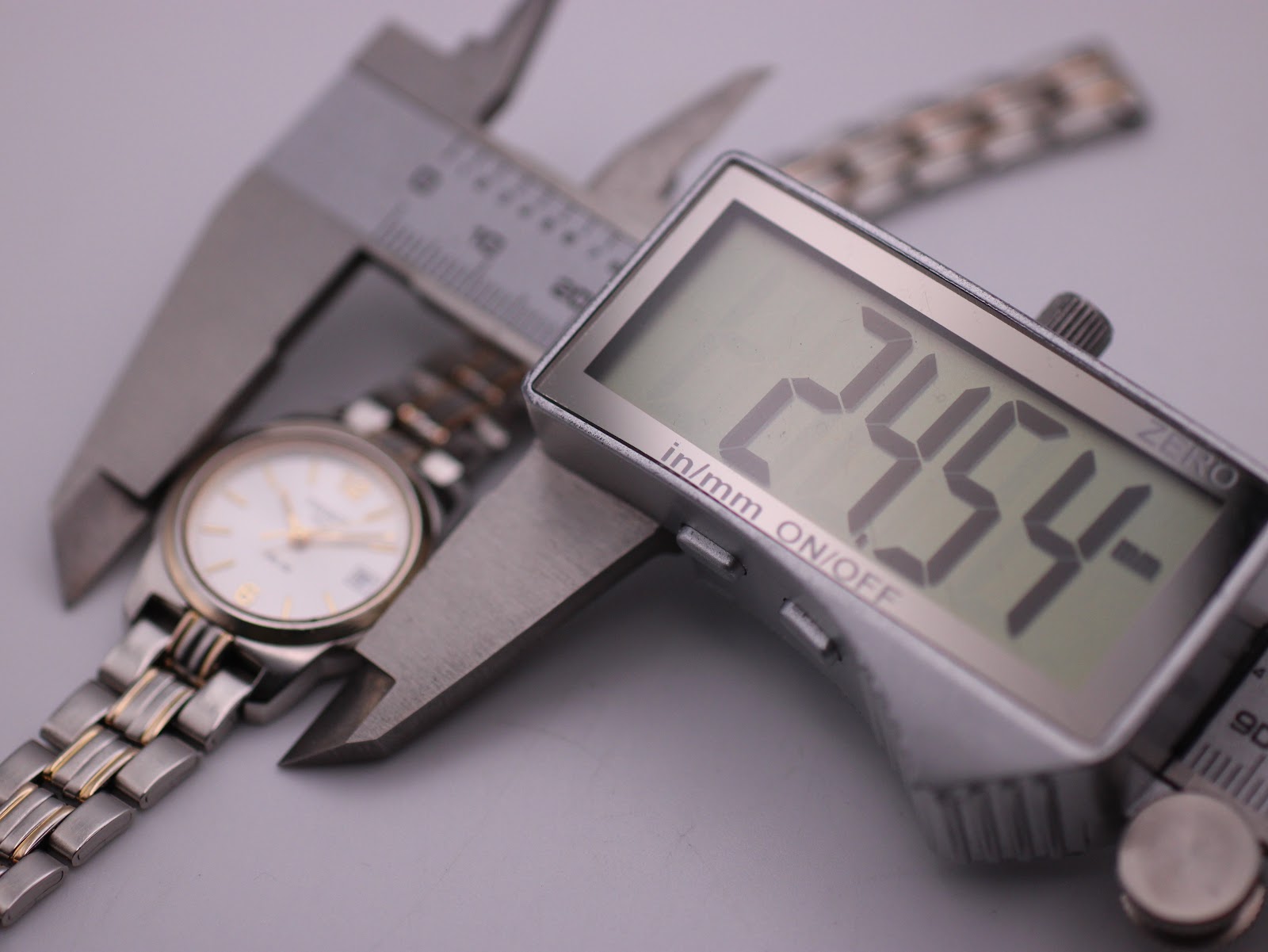 Digital caliper measuring the watch case diameter at 24.54mm.