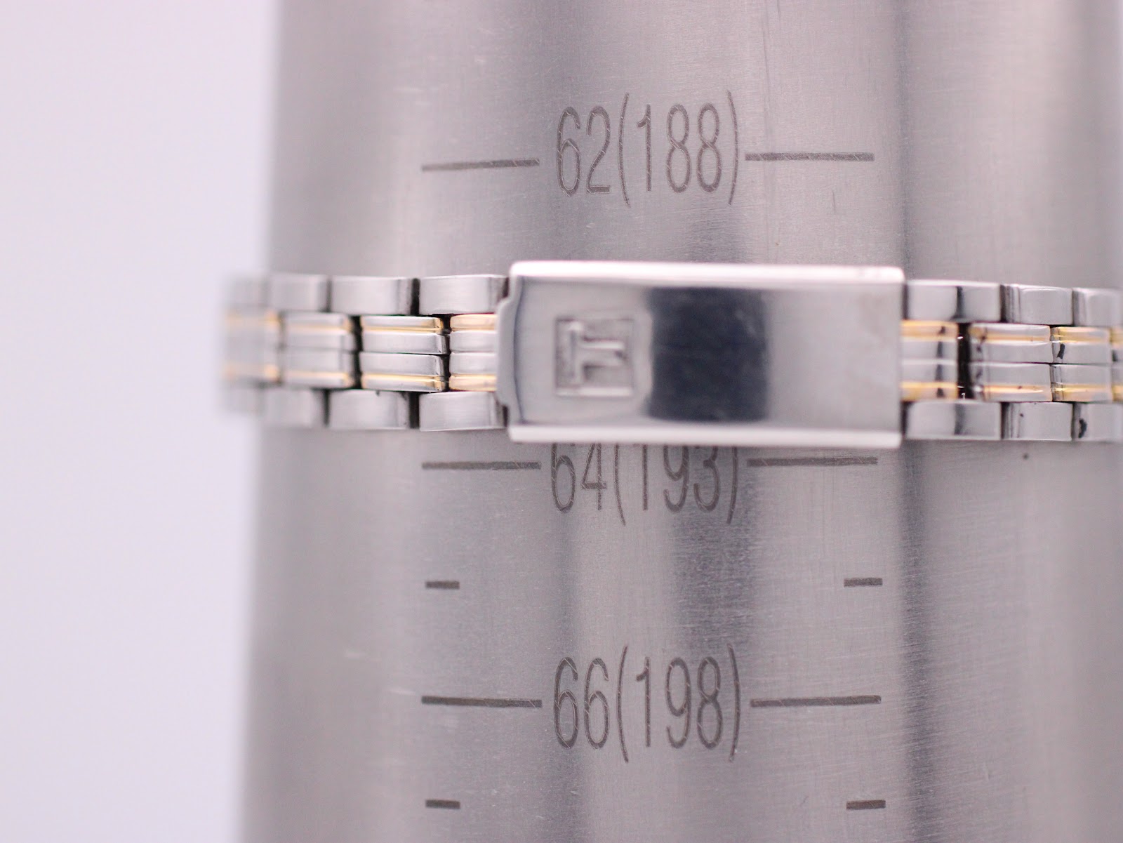 Close-up of the two-tone bracelet and signed fold-over clasp on a wrist sizing gauge, showing a wrist circumference of 188mm.