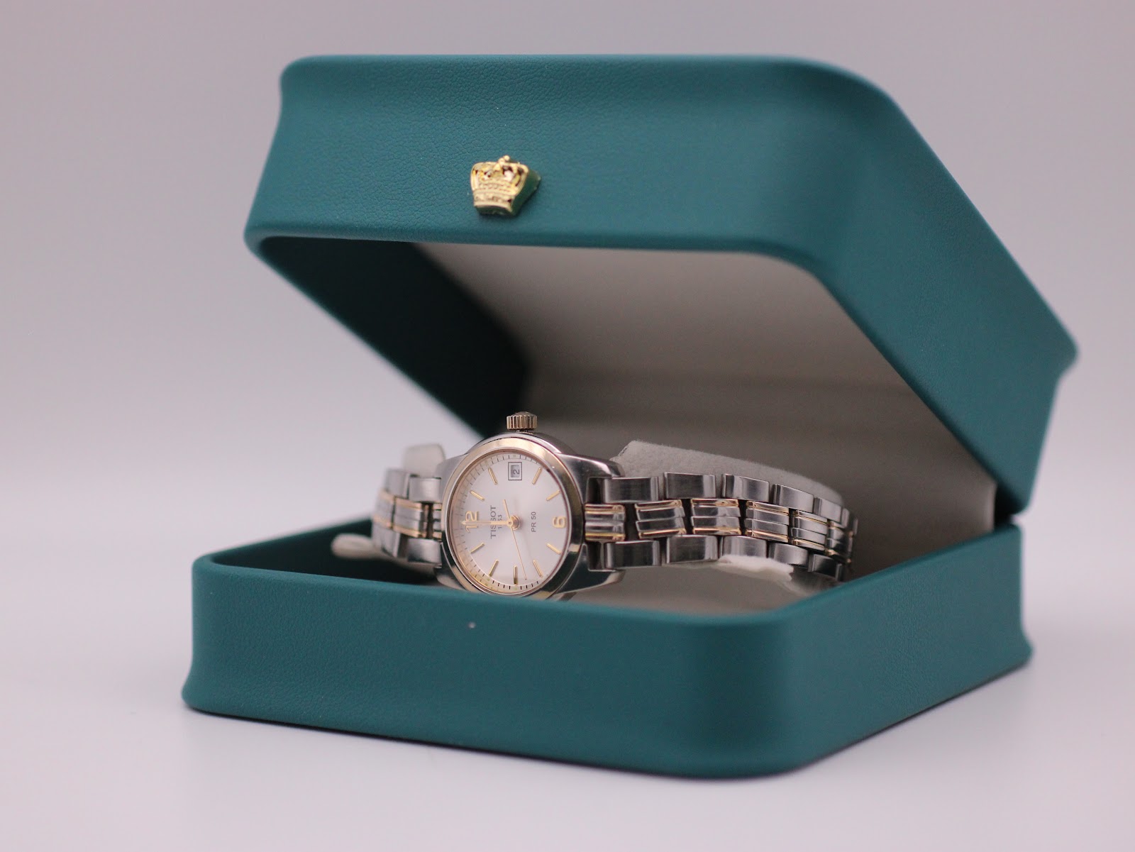 The Tissot watch resting in a green leatherette display box.