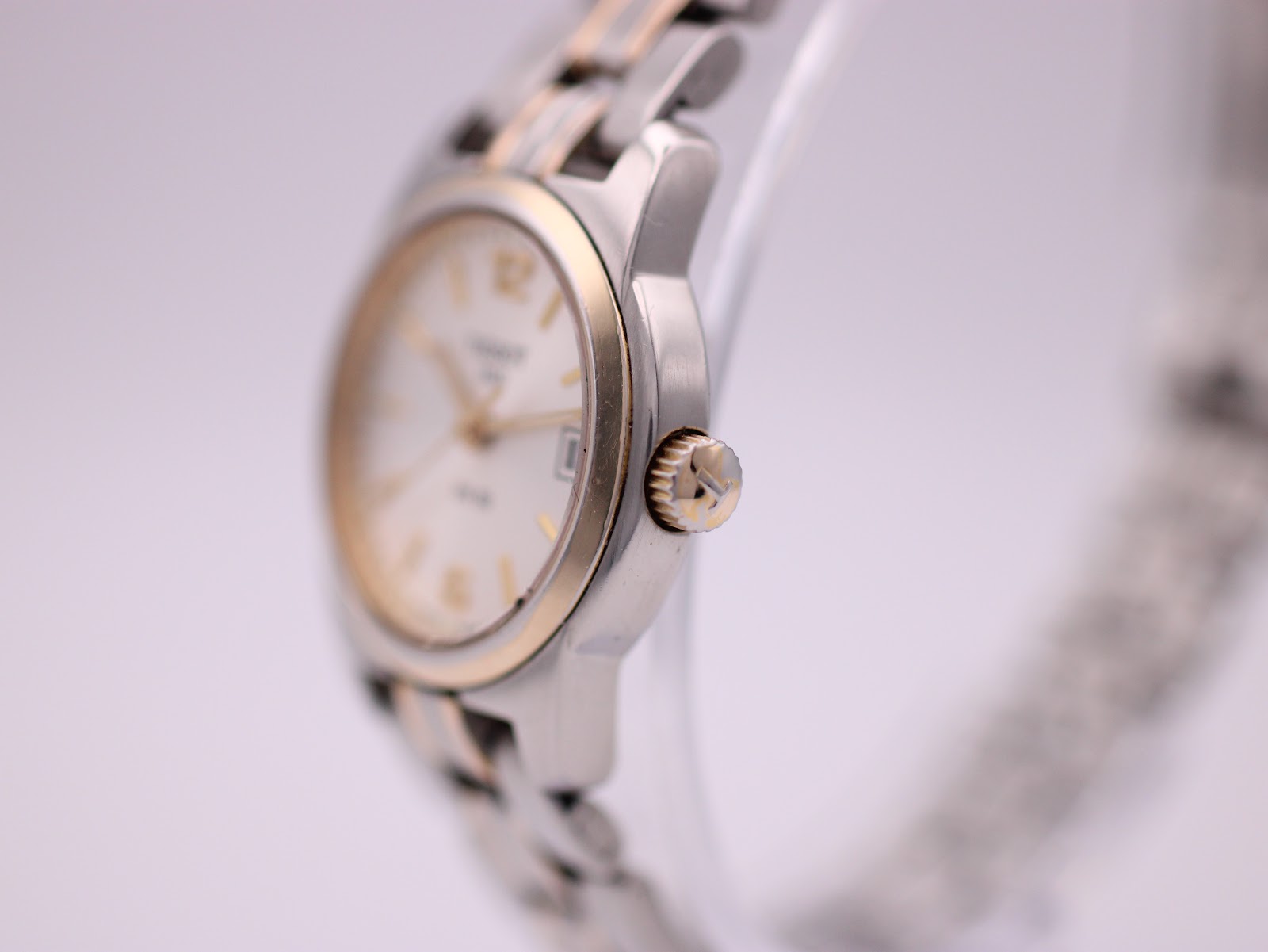 Side view of the watch case and crown, highlighting the gold-tone bezel.