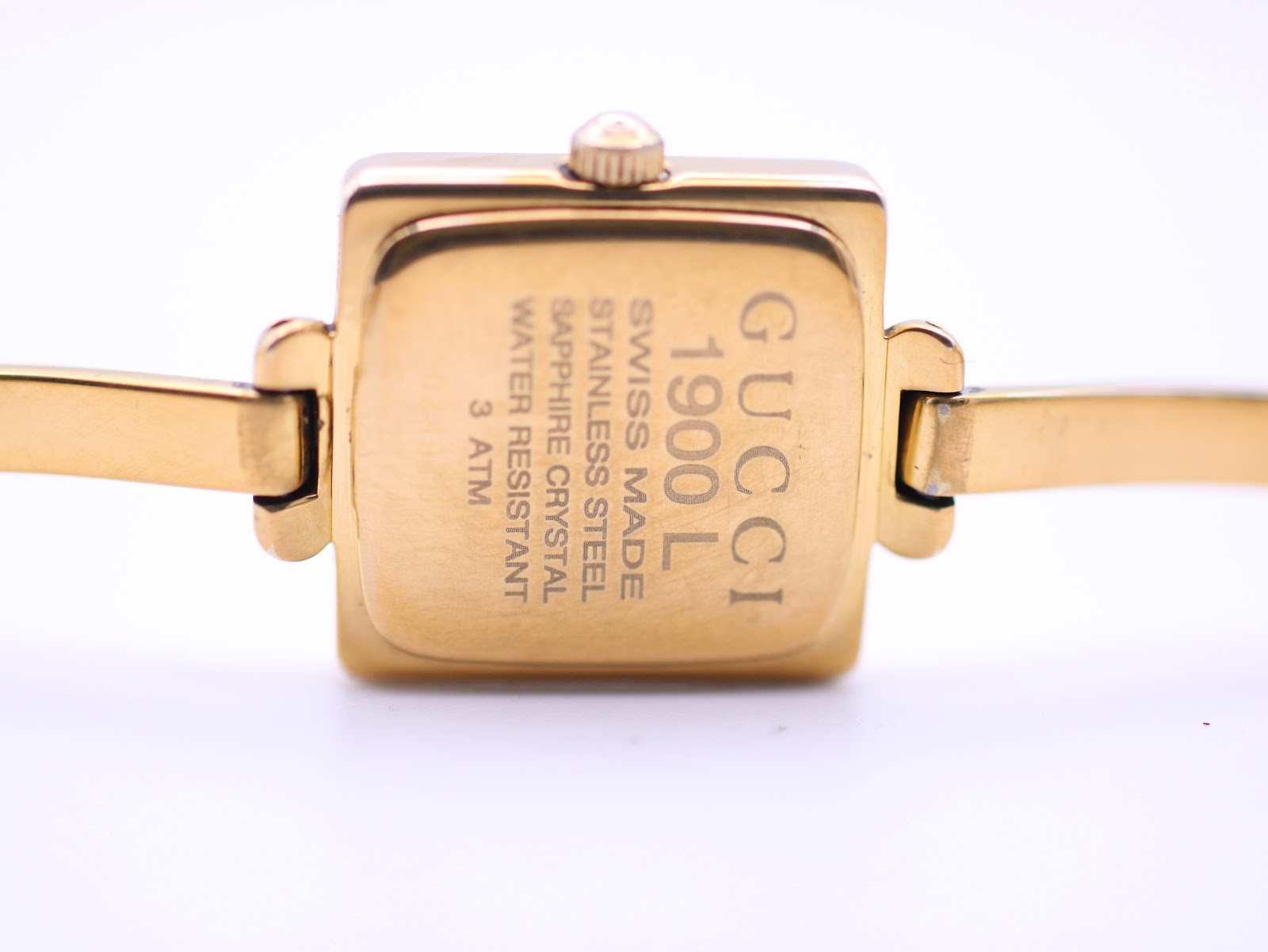 Close-up of the watch case back, with engravings 'GUCCI 1900L SWISS MADE STAINLESS STEEL SAPPHIRE CRYSTAL WATER RESISTANT 3 ATM'.