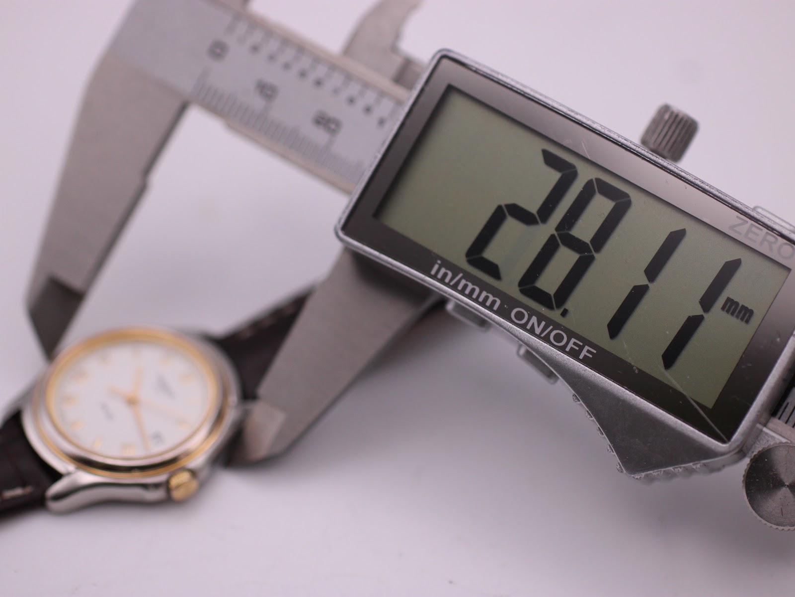 A digital caliper measuring the case diameter of the Tissot PR 50 watch, displaying a precise reading of 28.11mm.