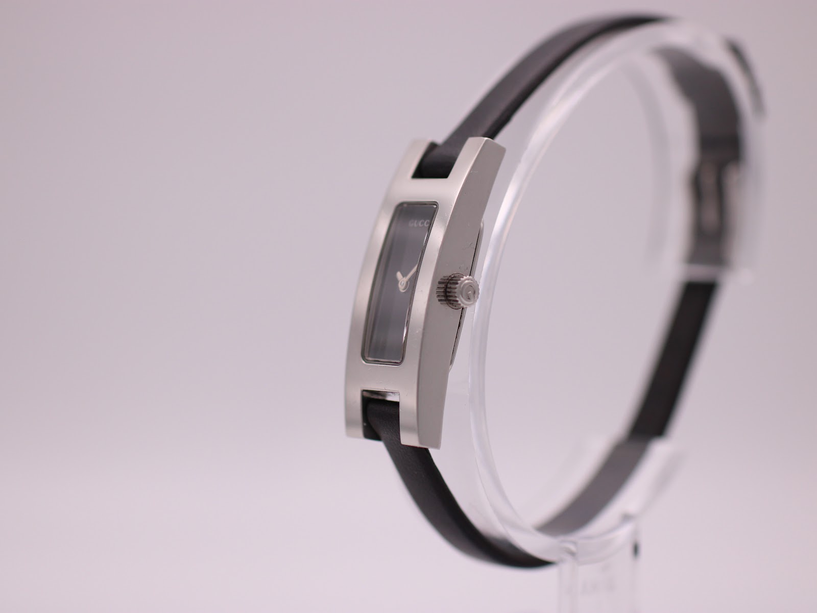 Angled side view of the Gucci 3900L watch on a stand, highlighting its slim profile and crown.
