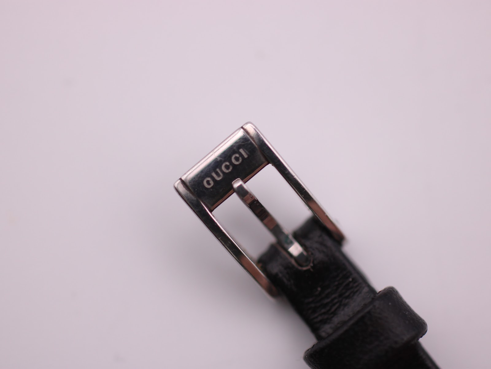 Close-up of the silver-tone buckle, clearly showing the "GUCCI" engraving.
