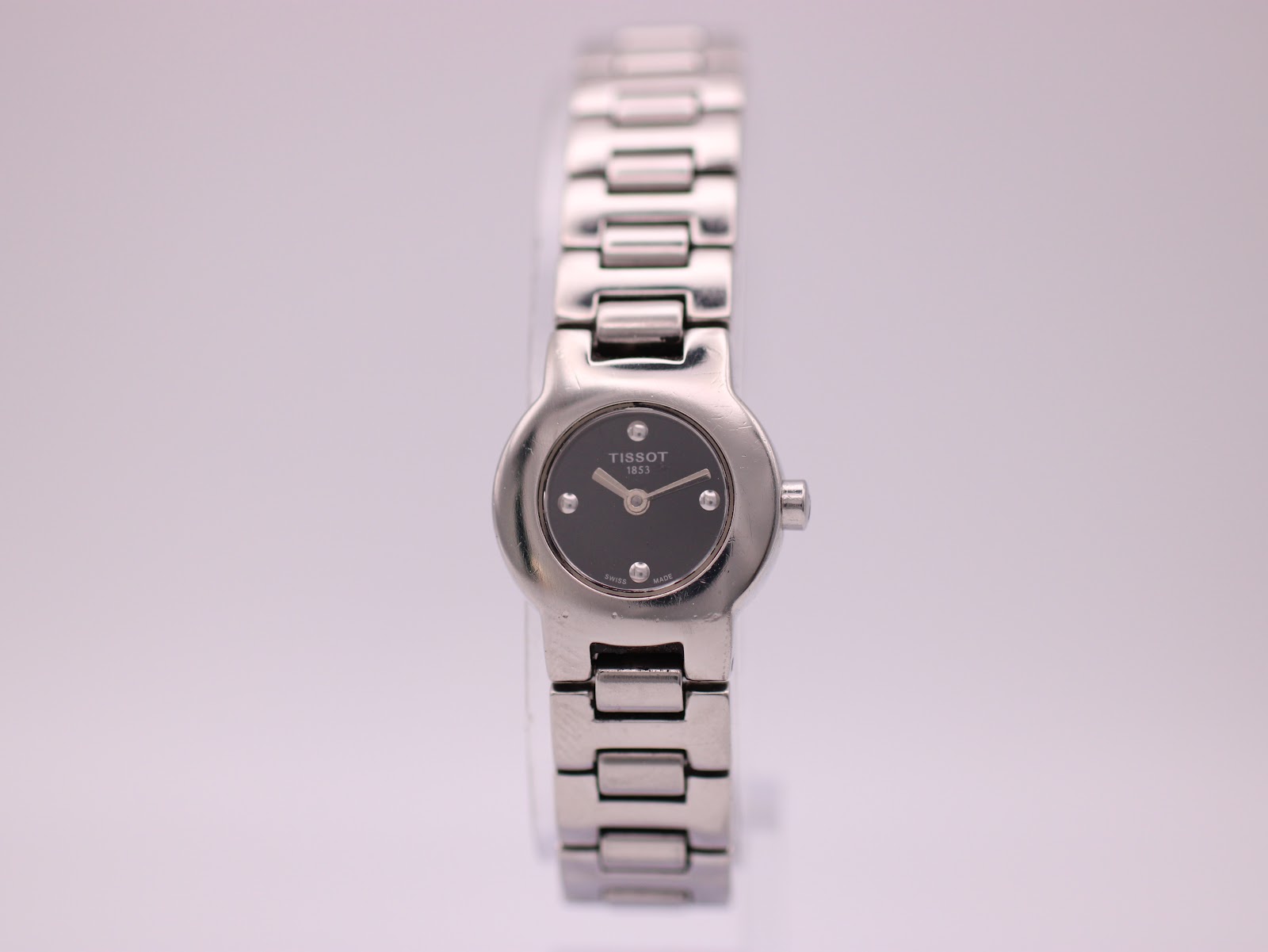 Front view of the Tissot G331K ladies' watch with black dial and integrated silver-tone bracelet.