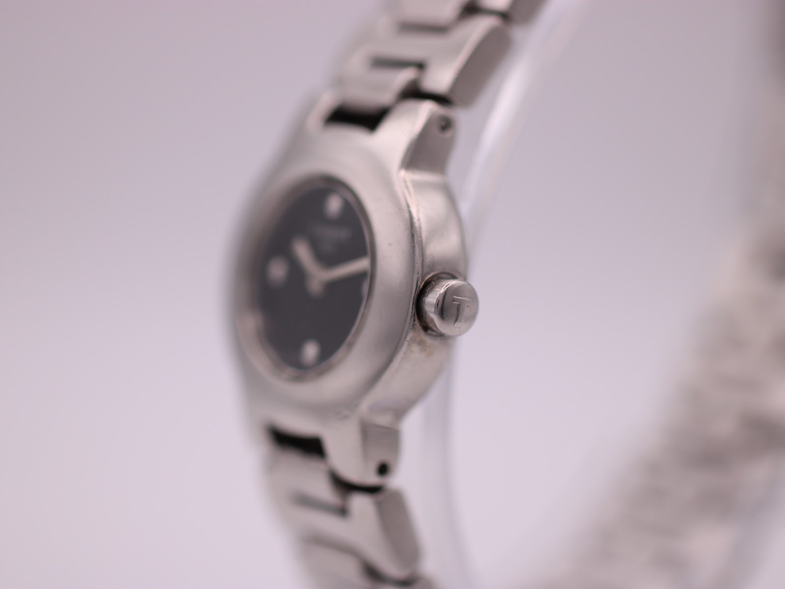 Side profile view of the Tissot watch case and signed crown, showing the integrated bracelet.