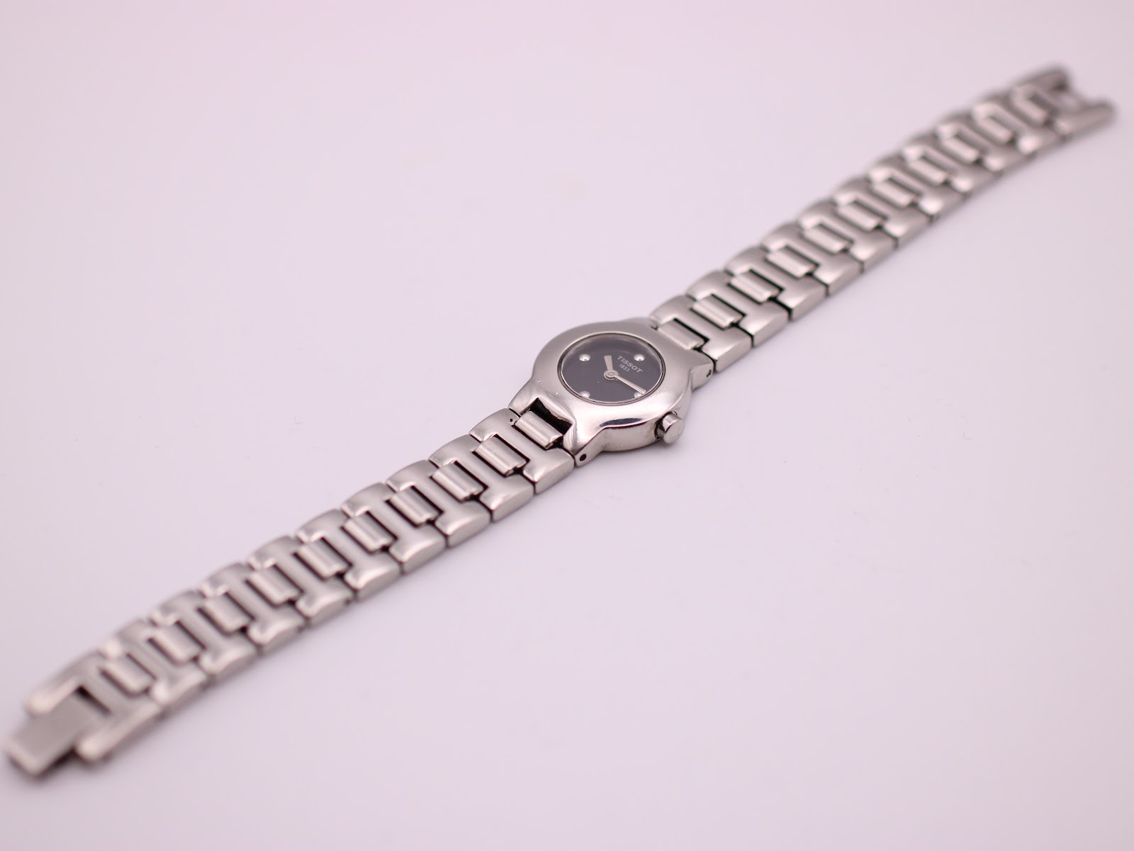 Full length overhead view of the Tissot G331K watch and its integrated silver-tone bracelet.
