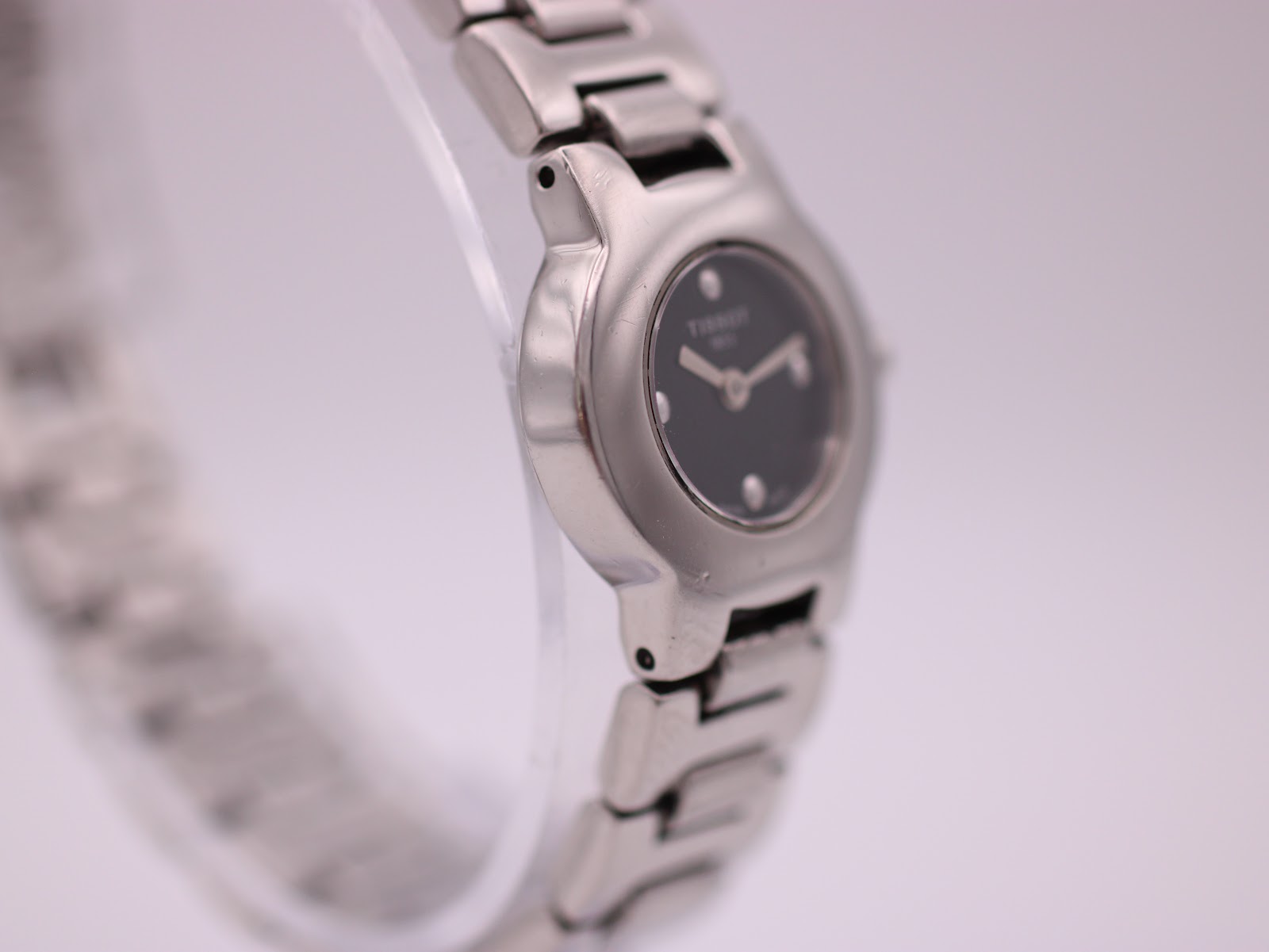 Angled side view of the Tissot watch case and bracelet, highlighting the smooth contours.
