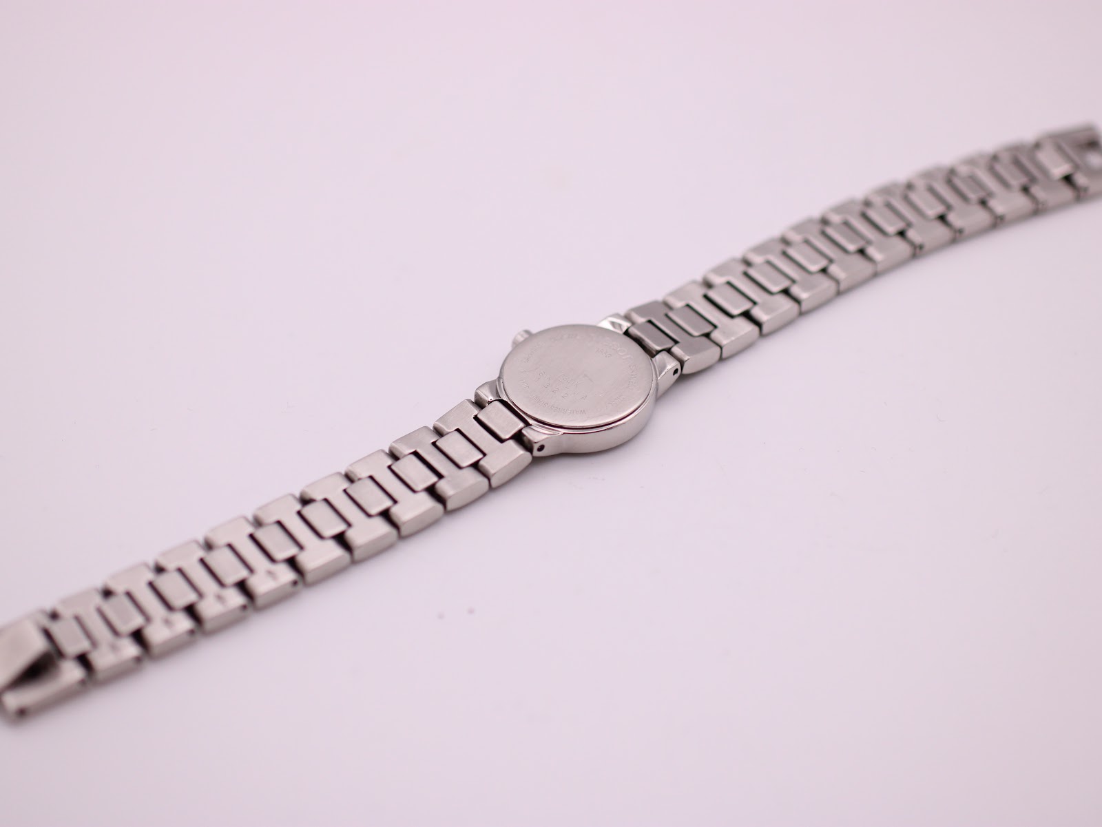 Angled back view of the Tissot watch, showing the case back and the full bracelet length.